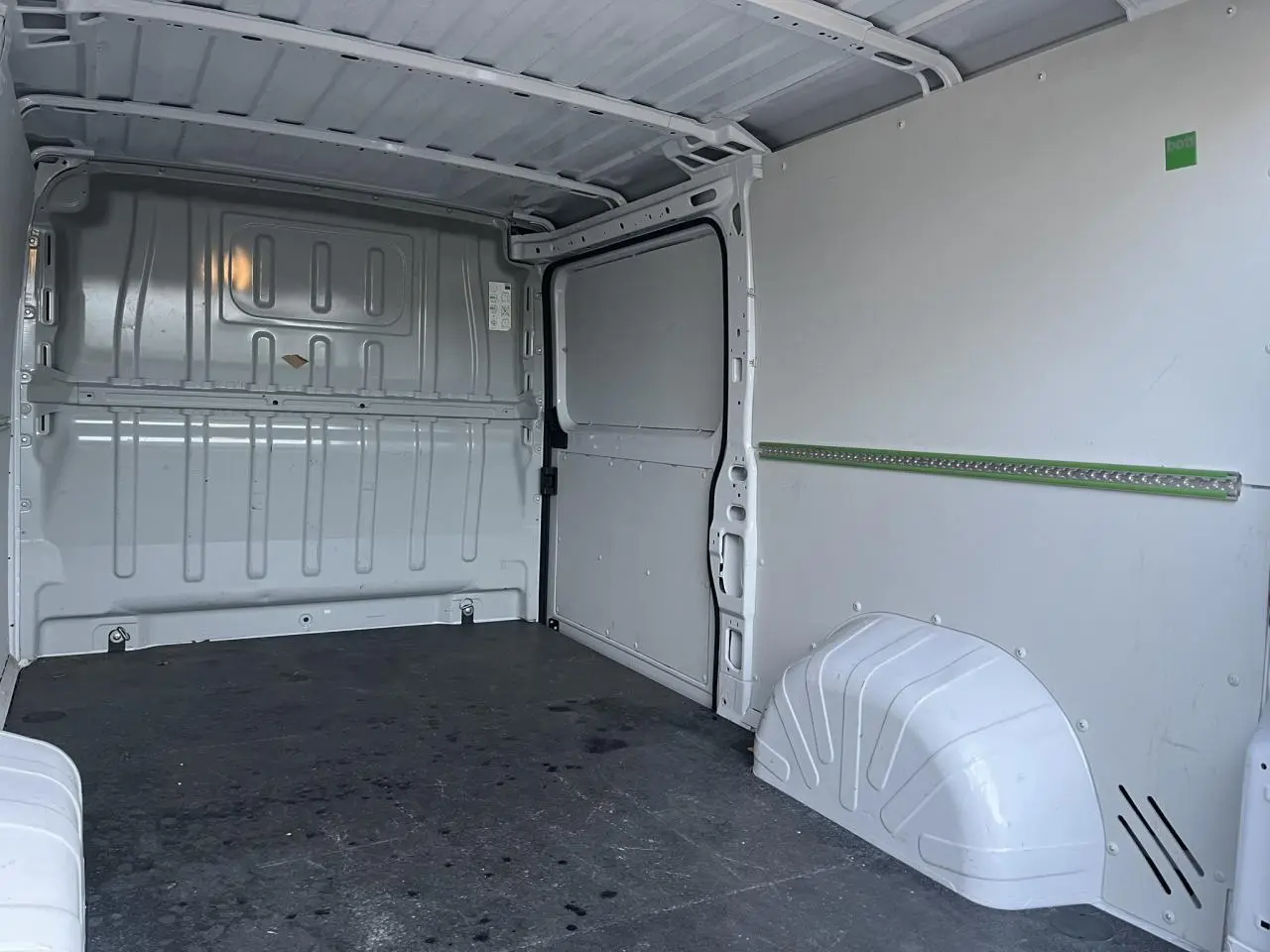 Intérieur du fourgon Opel Movano blanc vu de l'arrière, montrant le plancher et les parois métalliques.