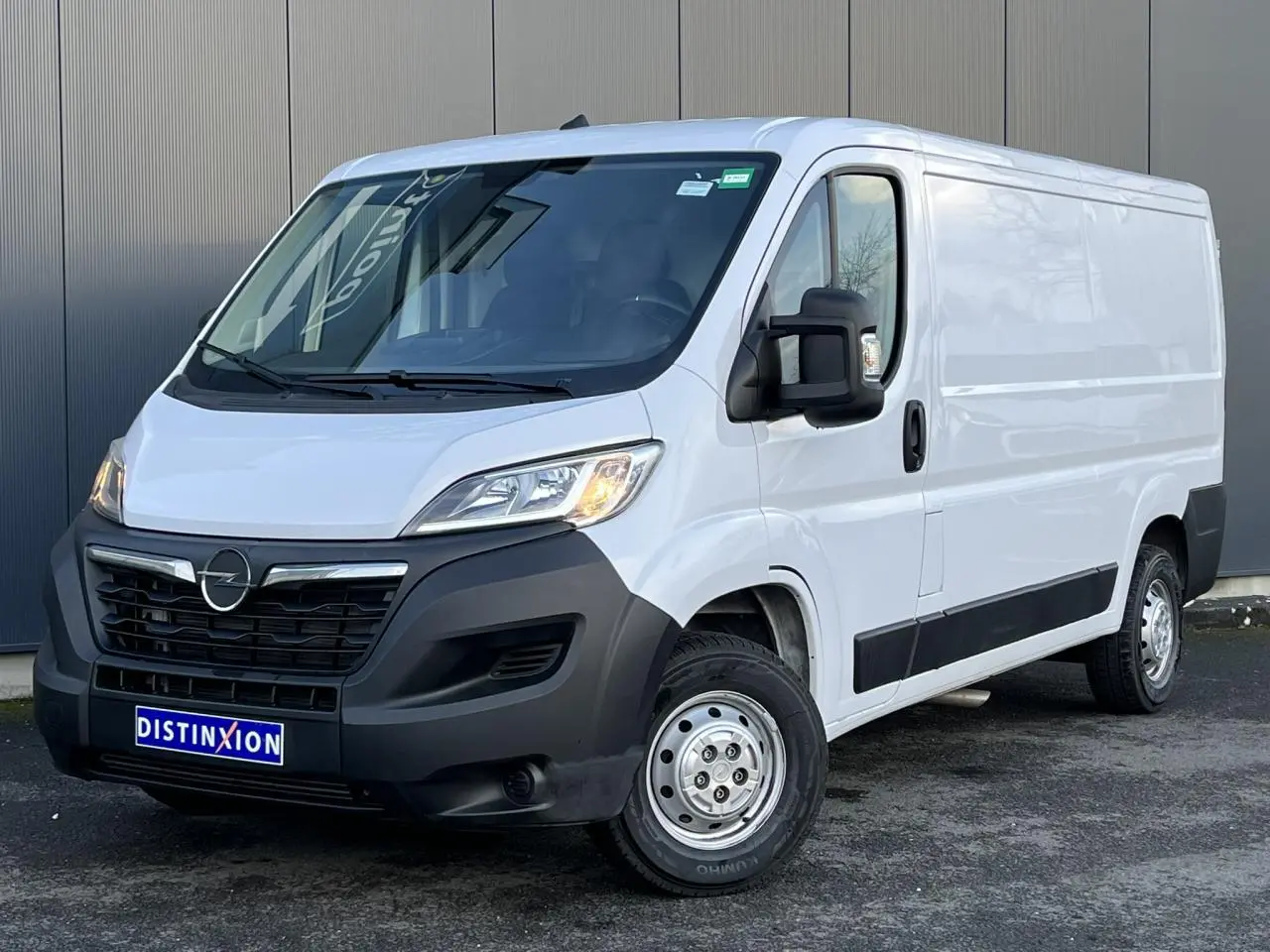 Opel Movano Fourgon blanc vu en 3/4 avant droit, avec pare-chocs noir et rétroviseurs électriques rabattables.