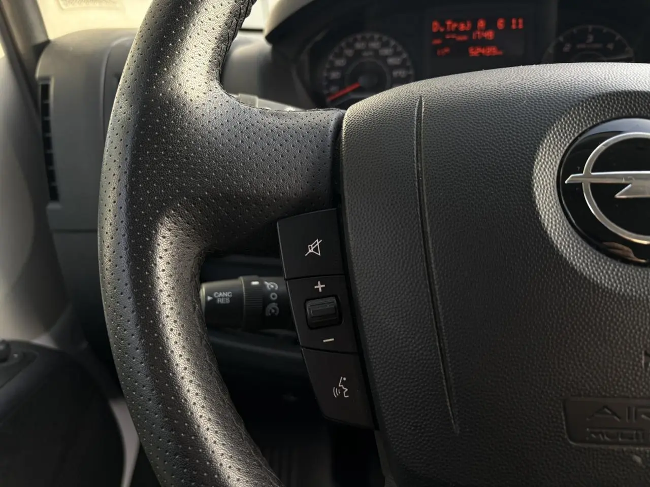 Gros plan sur le volant noir perforé de l'Opel Movano Fourgon 2024 avec commandes audio intégrées.