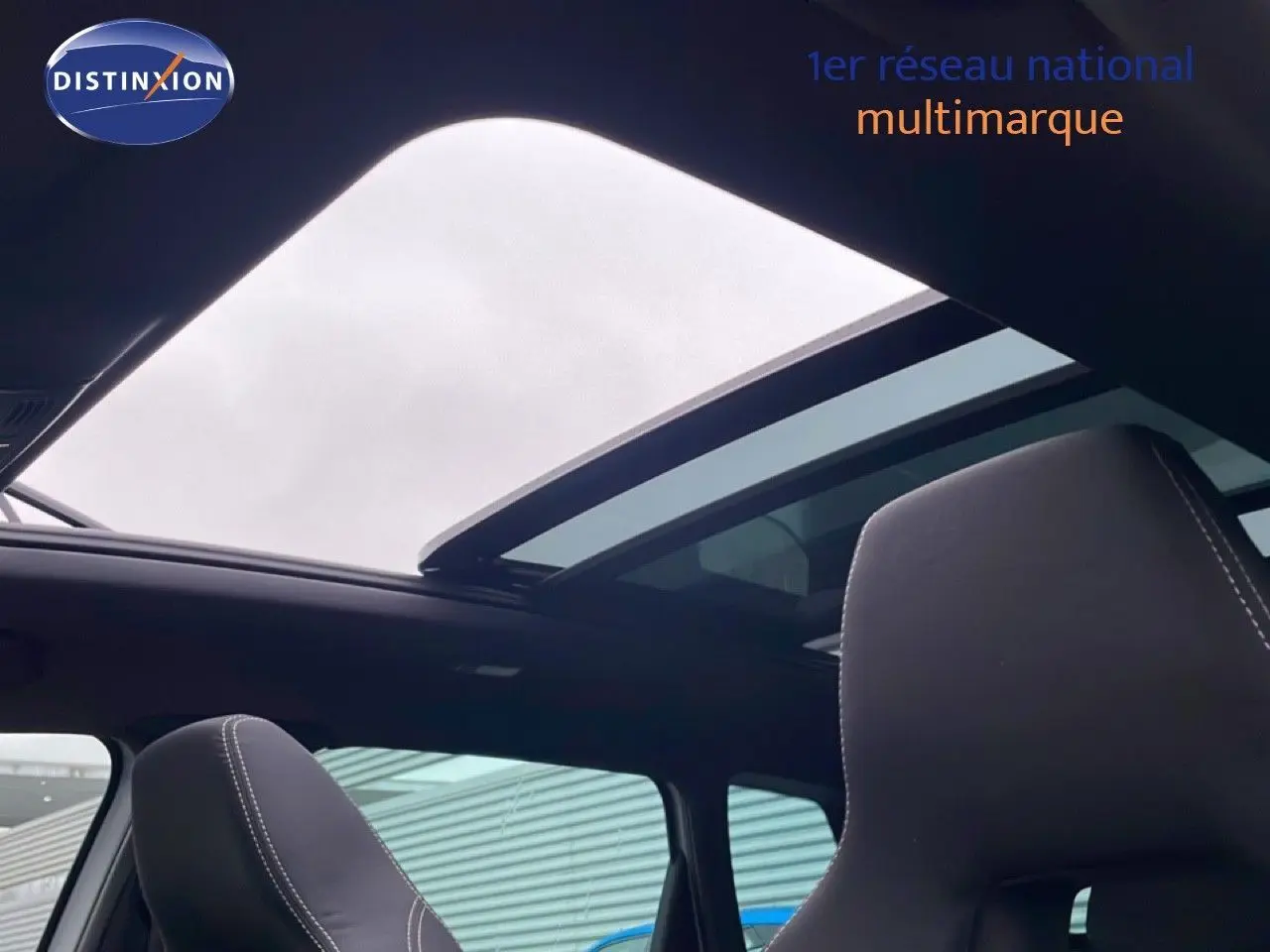 Vue intérieure du toit ouvrant panoramique et des sièges noirs avec surpiqûres blanches du Skoda Karoq gris argent 2025.