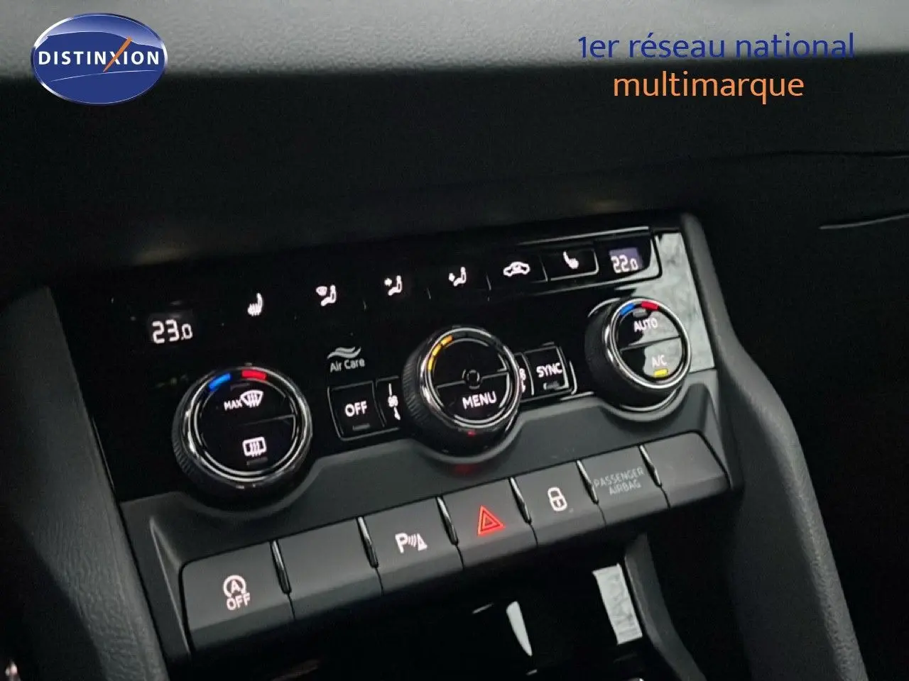 Gros plan sur la console centrale du Skoda Karoq gris argent, montrant les commandes de climatisation et les boutons de sécurité.