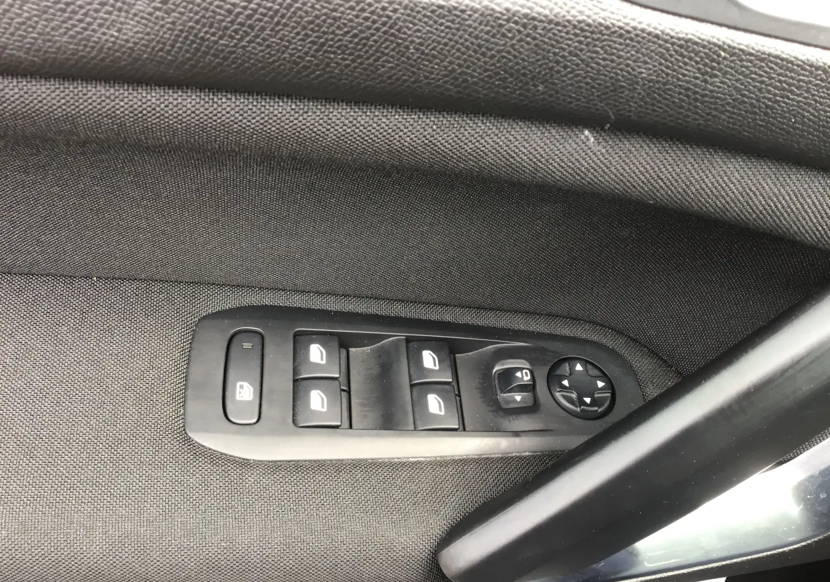 Gros plan sur les commandes de lève-vitres et réglage des rétroviseurs côté conducteur d’une Peugeot 308 gris Artense.