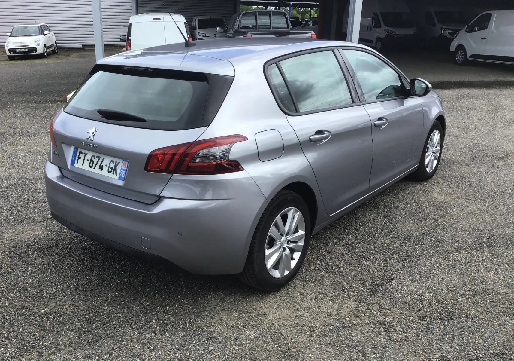 Peugeot 308 gris Artense vue 3/4 arrière droit, avec feux arrière distinctifs et jantes alliage 16 pouces.