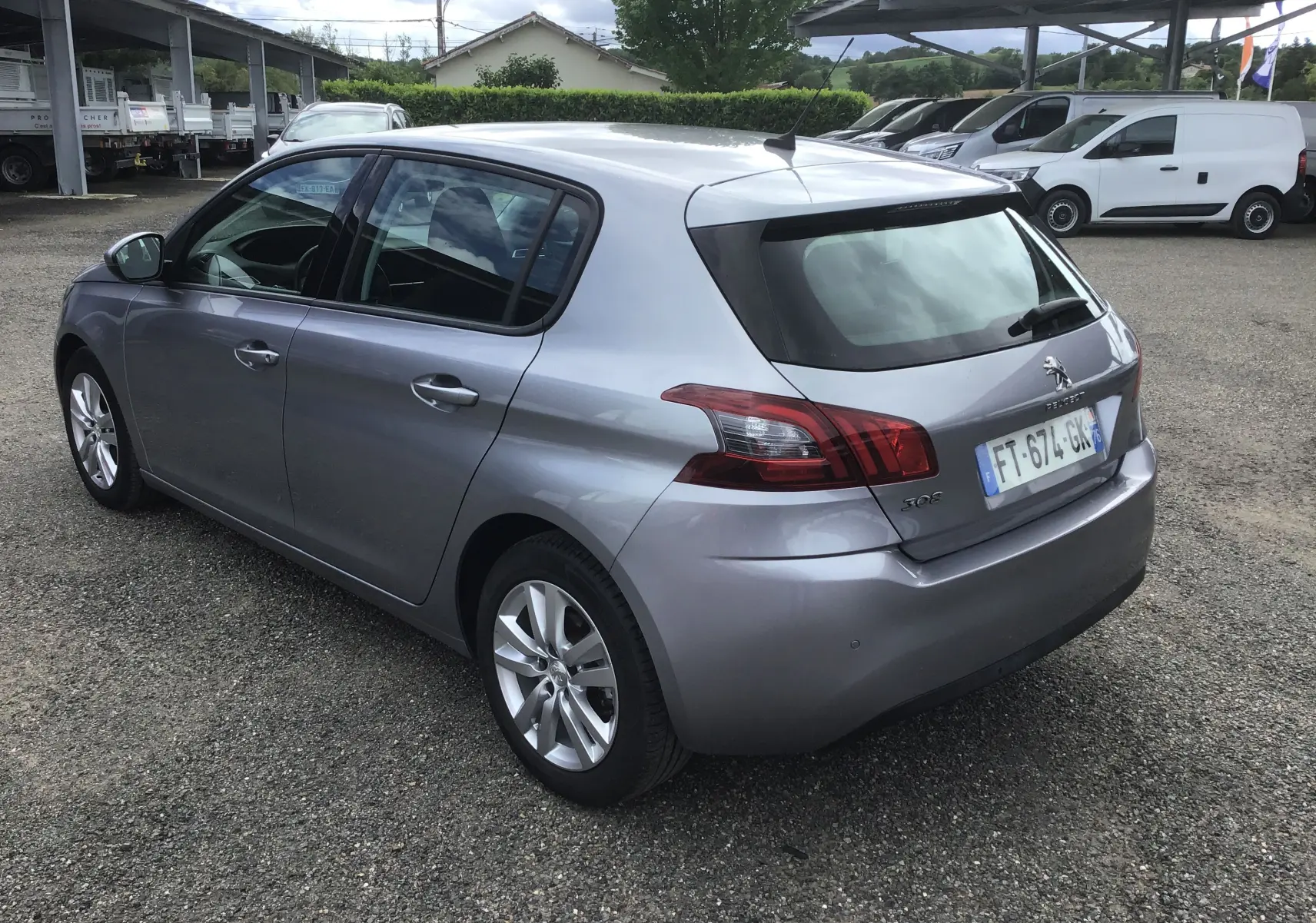 Peugeot 308 gris Artense vue 3/4 arrière droit, compacte cinq portes avec feux arrière caractéristiques et jantes alliage.