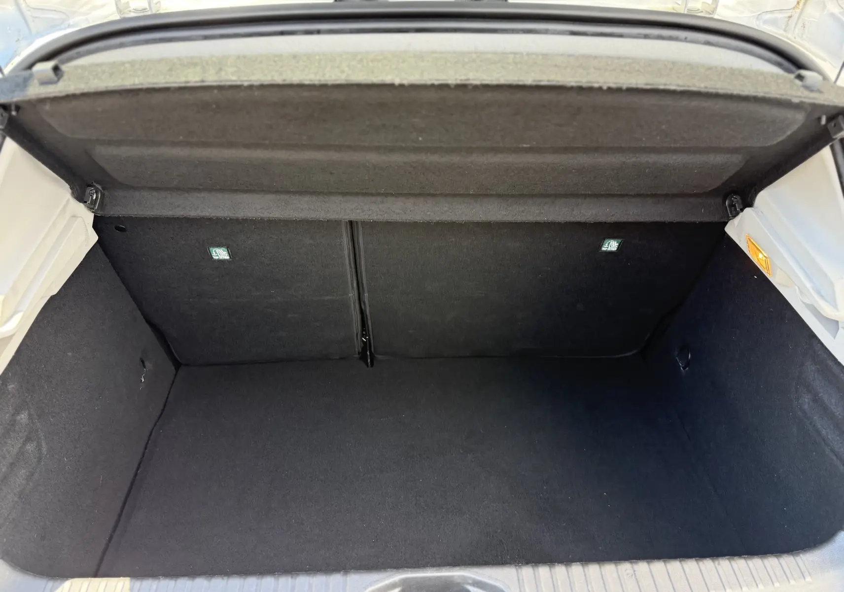 Vue intérieure du coffre ouvert d'une Renault Clio V gris, montrant un espace de rangement propre et bien fini.