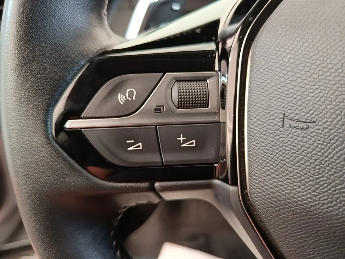 Gros plan sur les commandes de volume et téléphone du volant cuir du Peugeot 2008 gris clair, version 2022.