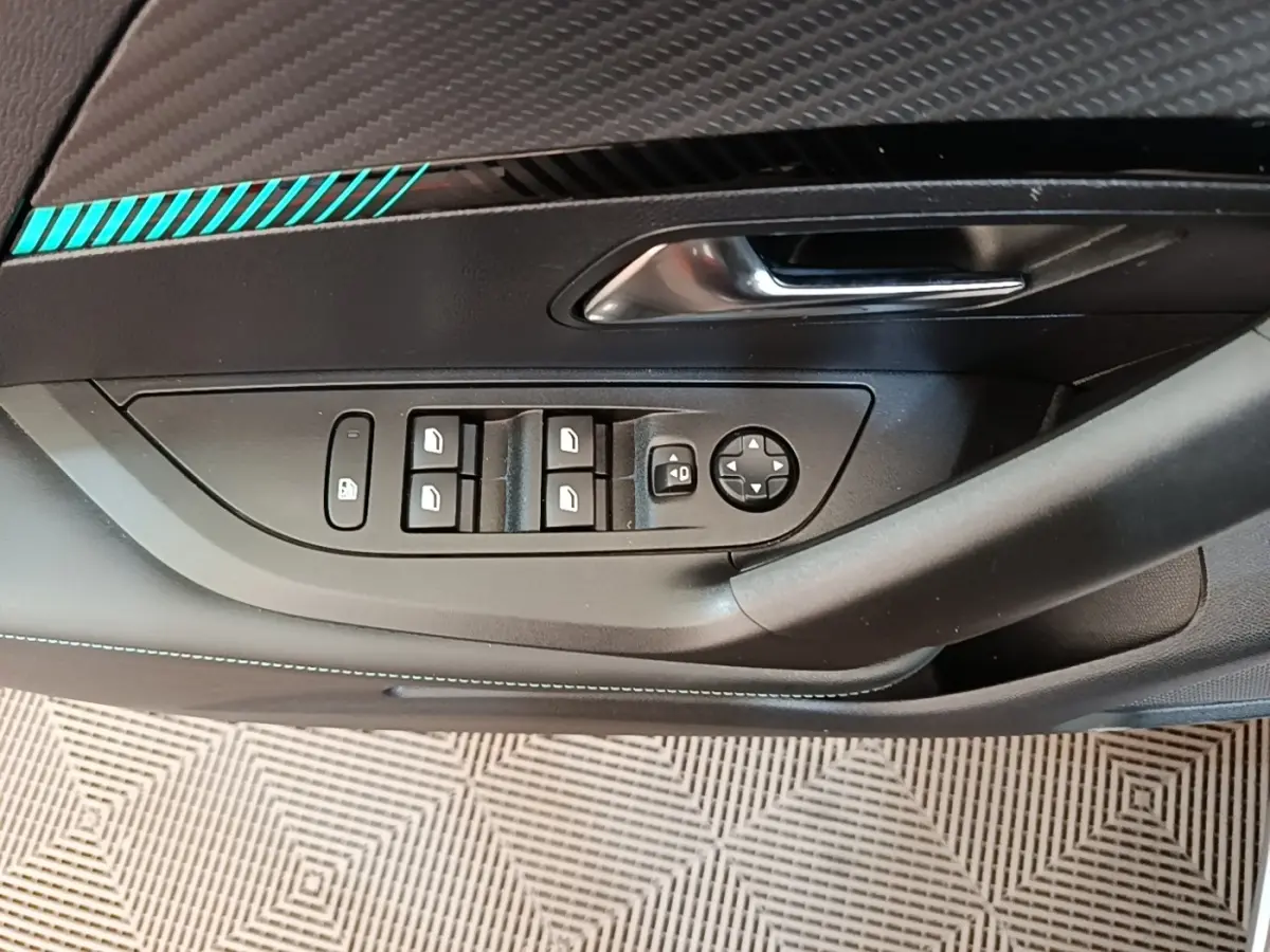 Gros plan sur la commande des vitres et rétroviseurs côté gauche du Peugeot 2008 gris clair avec surpiqûres bleues.