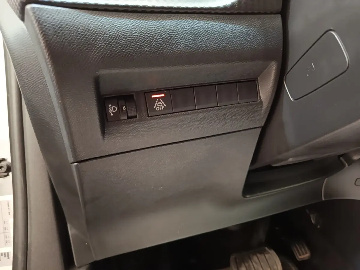Détail intérieur côté gauche du tableau de bord noir avec commandes d'aide à la conduite sur Peugeot 2008 gris clair.