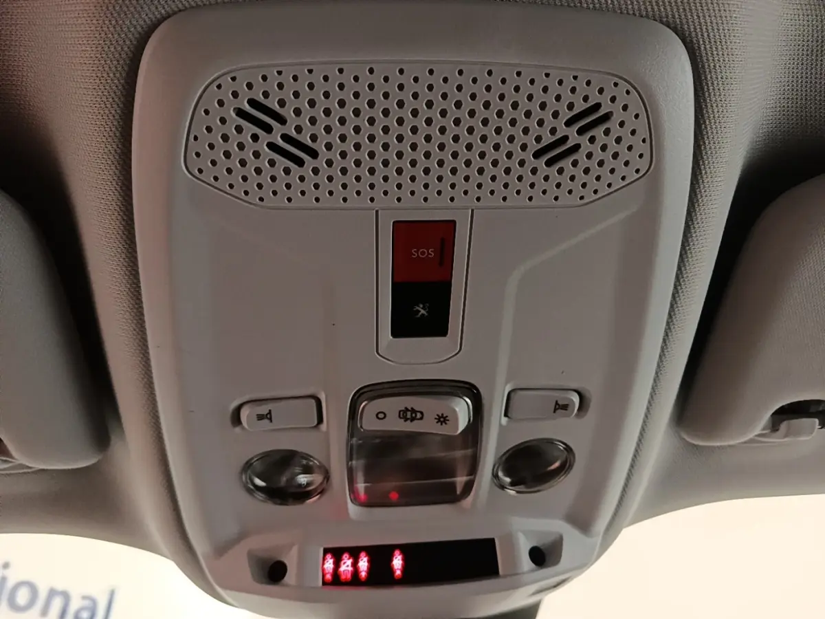 Vue intérieure du plafonnier avant du Peugeot 2008 gris clair, avec boutons d’éclairage et alerte SOS rouge.