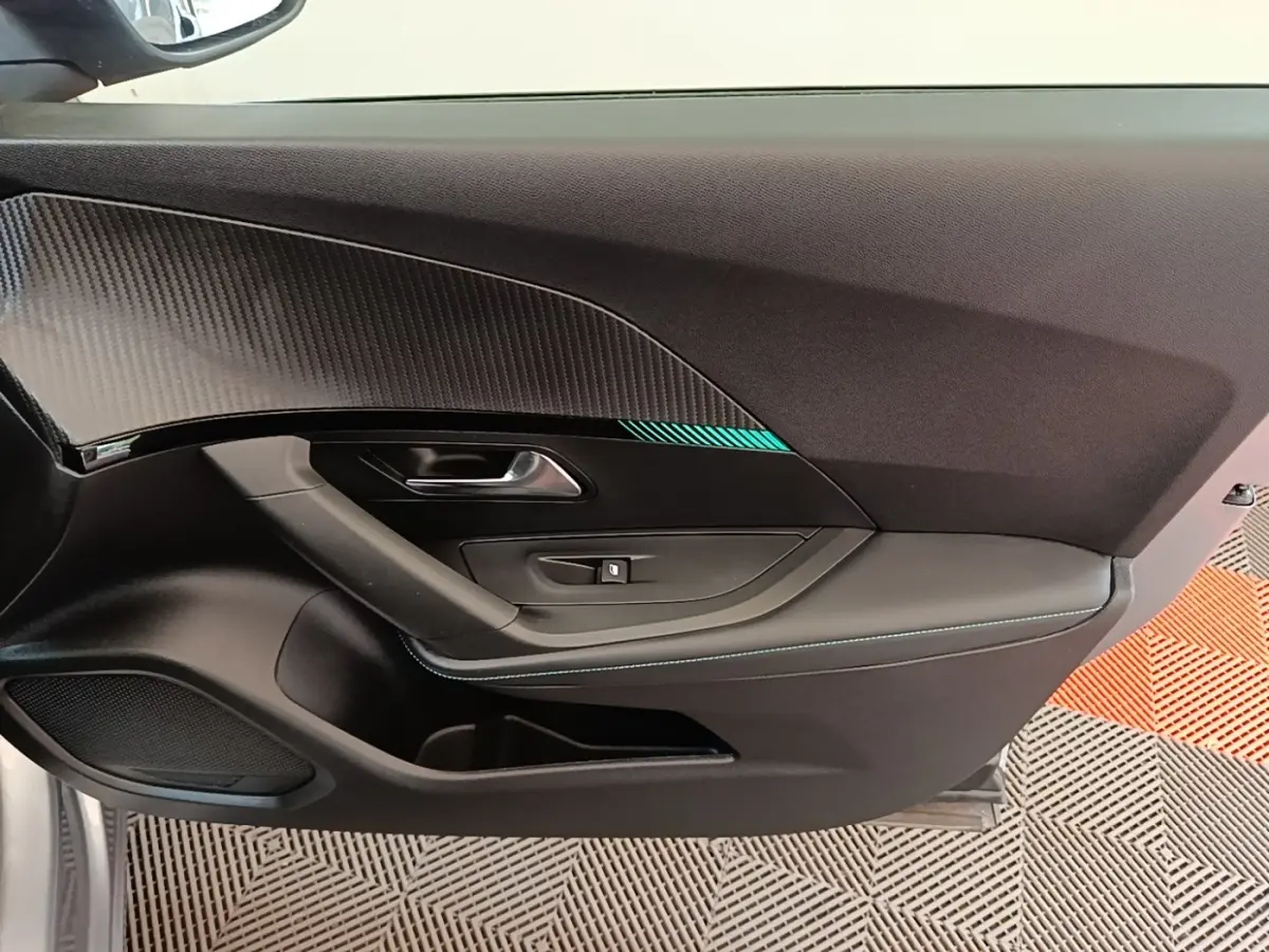 Vue rapprochée de la porte avant gauche du Peugeot 2008 gris clair avec insert décoratif et surpiqûres bleues.