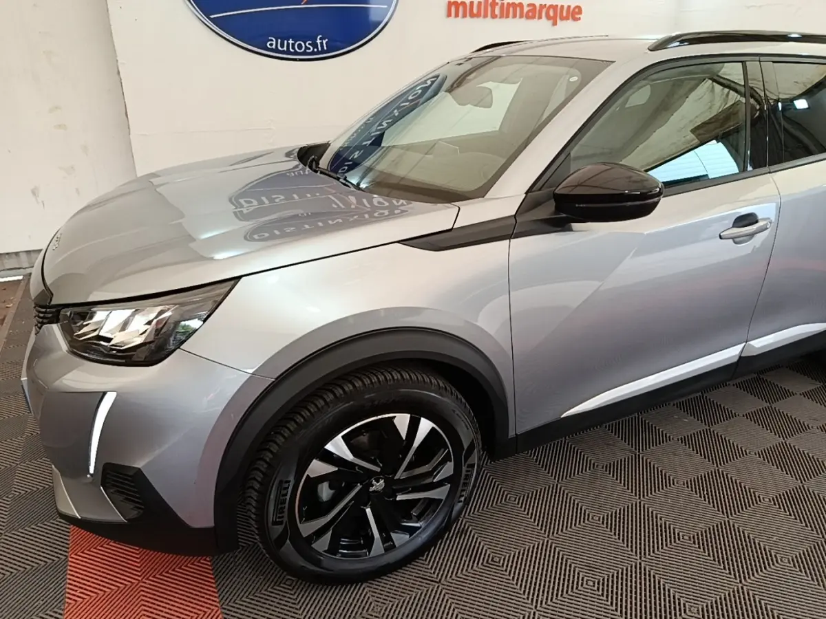 Vue 3/4 avant gauche d’un Peugeot 2008 gris clair avec jantes noires et rétroviseur noir brillant.