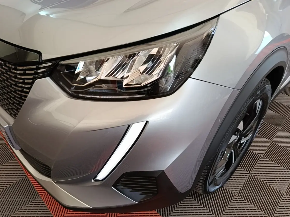 Gros plan sur l'avant droit gris clair du Peugeot 2008 2022, mettant en valeur le phare LED et la roue noire.