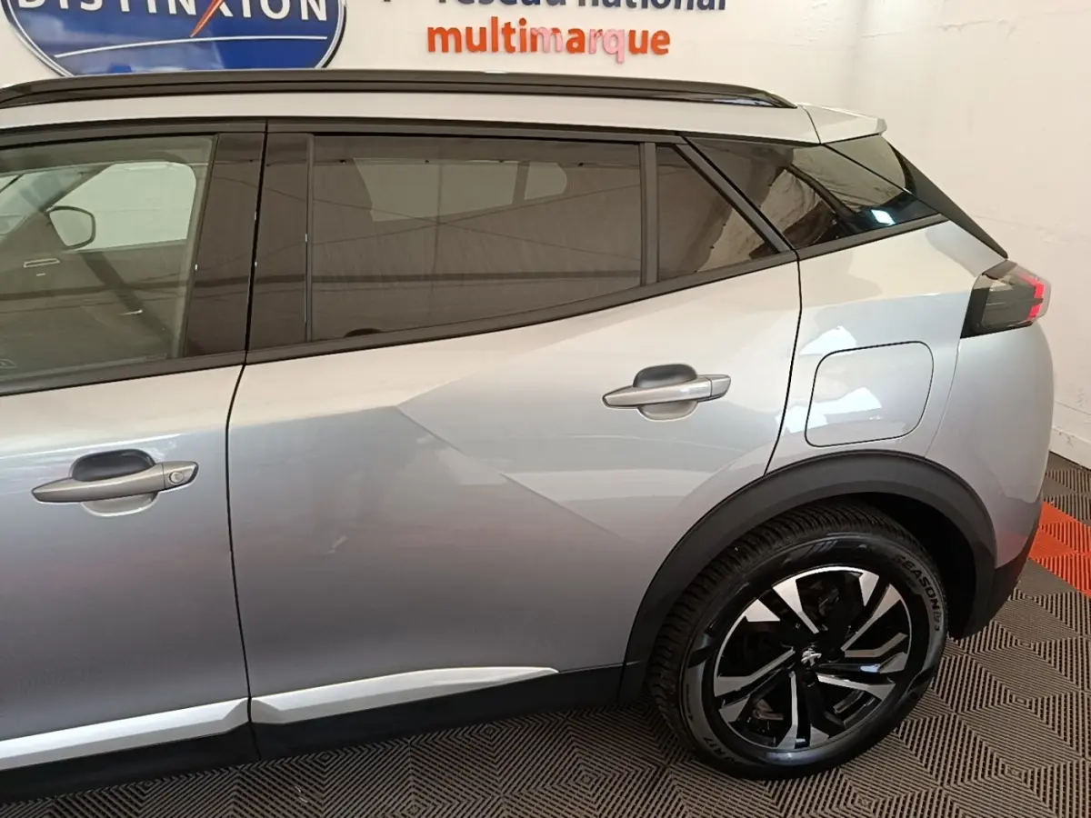 Vue latérale côté droit du Peugeot 2008 gris clair, mettant en valeur les vitres teintées et les jantes noires bicolores.