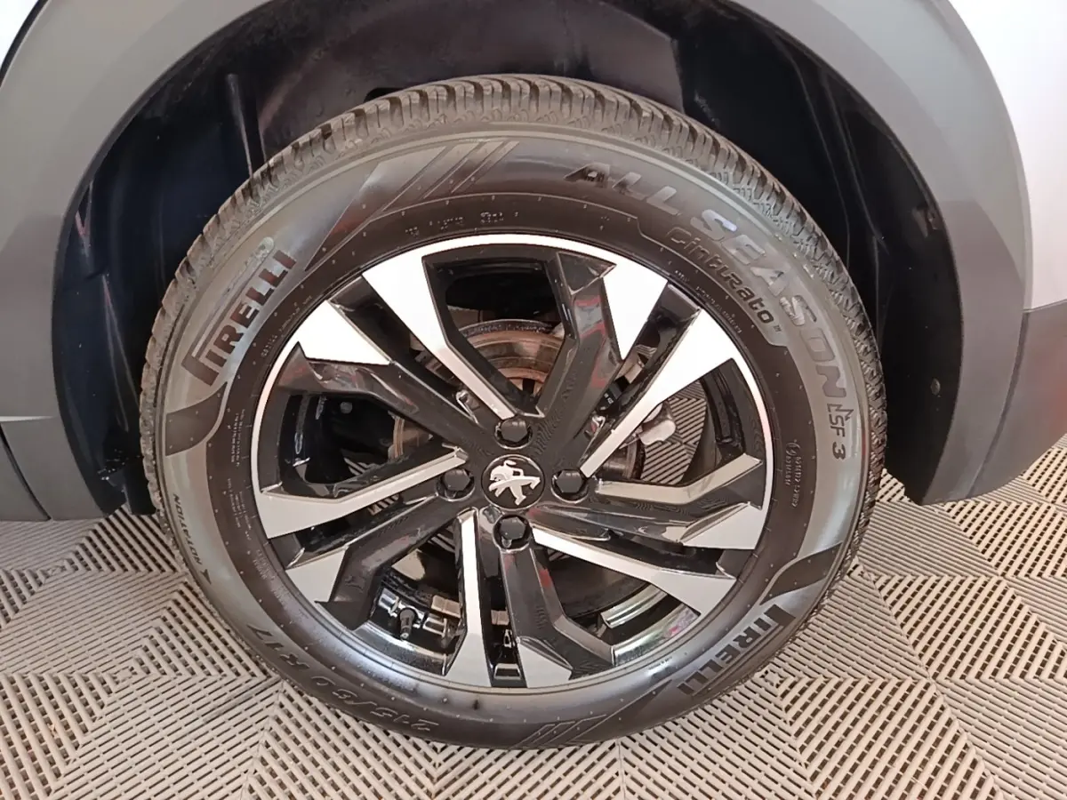 Gros plan sur la roue avant droite d’un Peugeot 2008 gris clair avec jante alliage noire et argentée, pneu Pirelli.