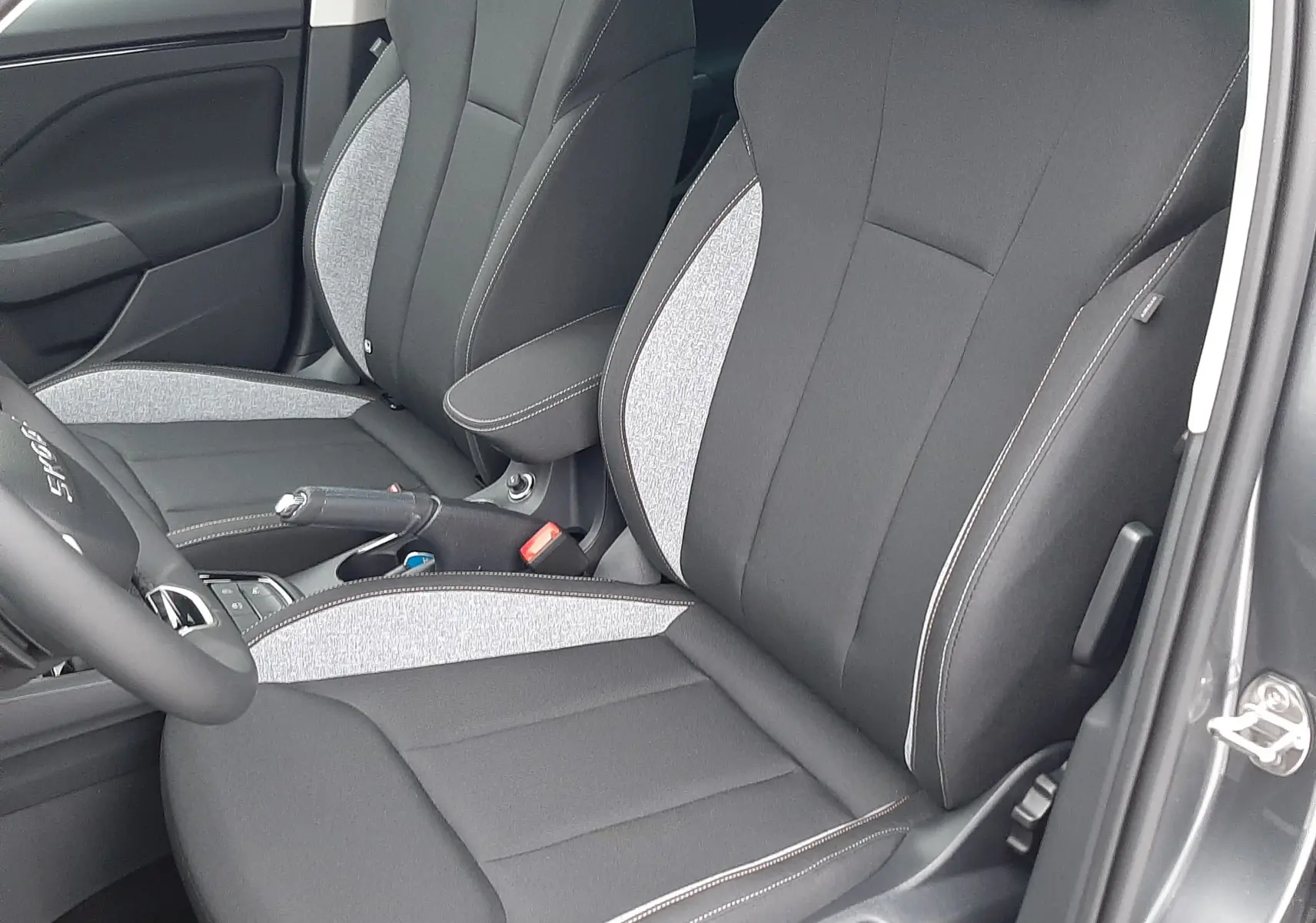 Vue rapprochée des sièges avant noirs et gris du Skoda Kamiq 2025, version 1.0 TSI, avec portière ouverte côté conducteur.