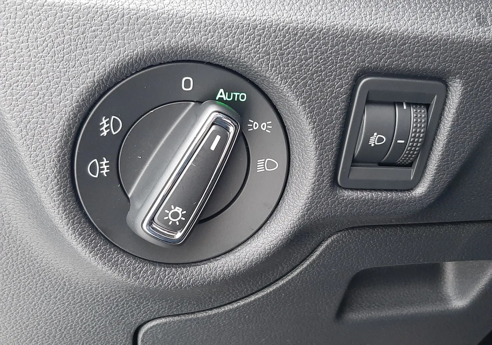 Gros plan sur le sélecteur de phares avec mode automatique et réglage d'intensité lumineuse dans un Skoda Kamiq 2025.