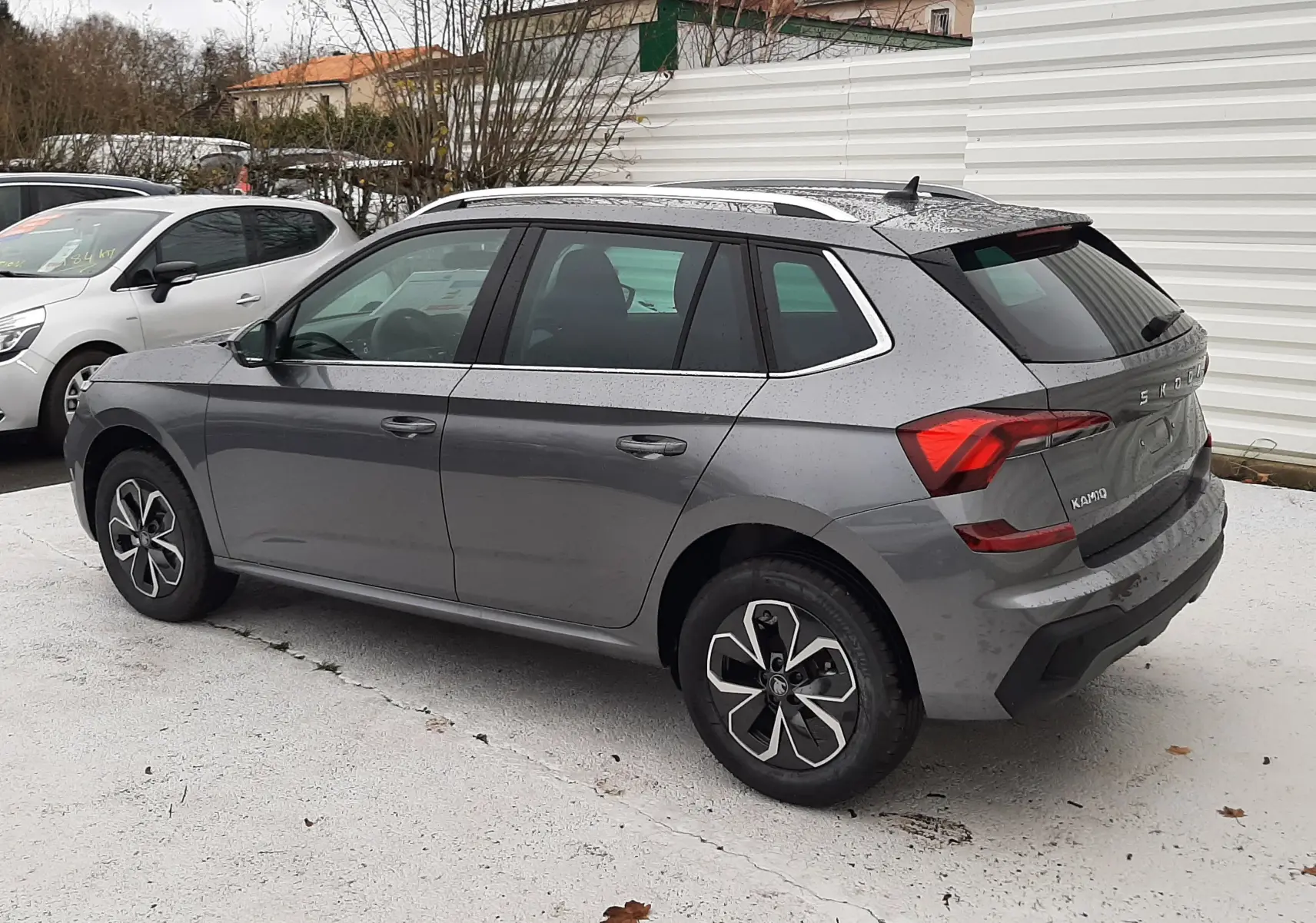 Vue 3/4 arrière côté gauche d'un Skoda Kamiq gris graphite métallisé avec jantes noires et toit ouvrant.