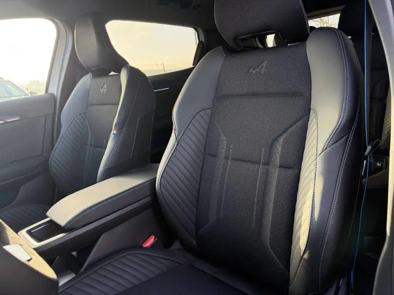 Gros plan sur les sièges avant noirs du Renault Scénic E-Tech 2025 avec logo Alpine brodé et surpiqûres bleues.