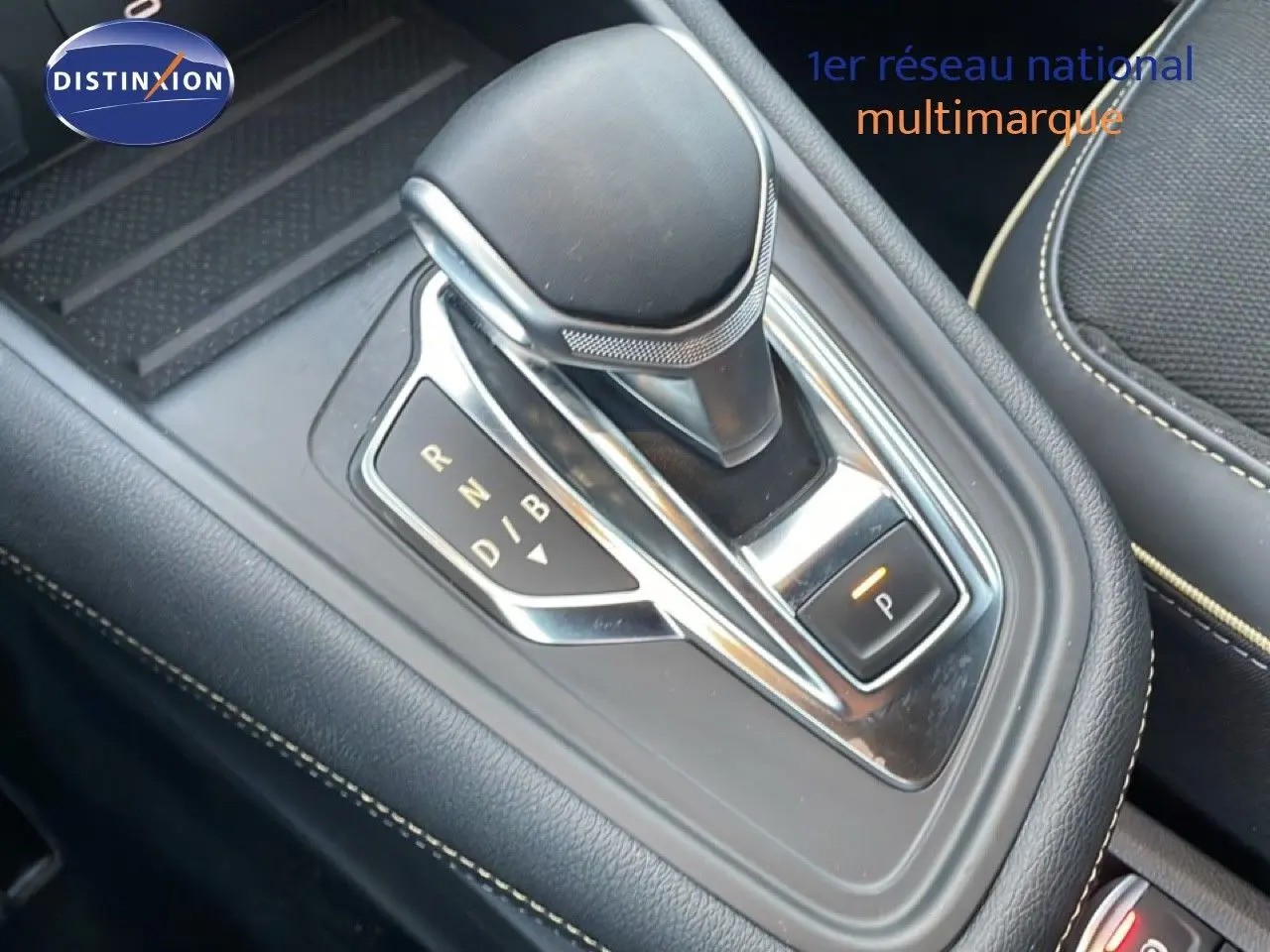 Gros plan sur le levier de vitesse automatique noir et chrome de la Renault Symbioz 2025, intérieur cuir noir avec surpiqûres beiges.