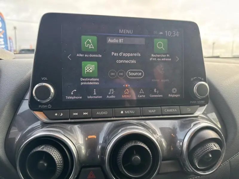 Vue rapprochée de l’écran tactile central et des commandes de climatisation du Nissan Juke gris perle métallisé, version 2022.
