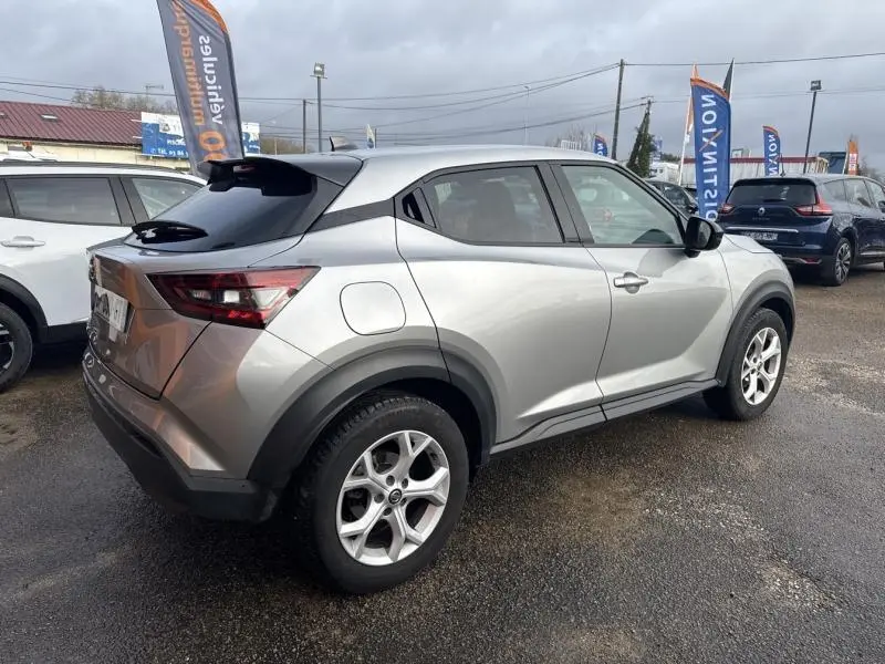 Vue 3/4 arrière droite d'un Nissan Juke 2022 gris perle métallisé avec jantes alliage et toit noir.