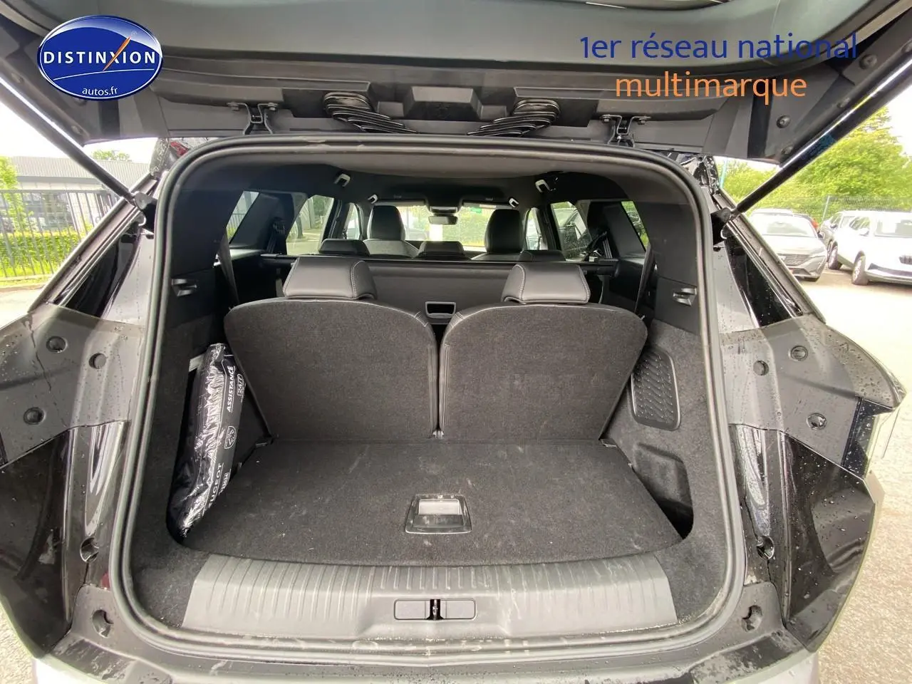 Coffre ouvert vu de l'arrière d'un Peugeot 5008 noir avec sièges arrière en position relevée, intérieur spacieux visible.