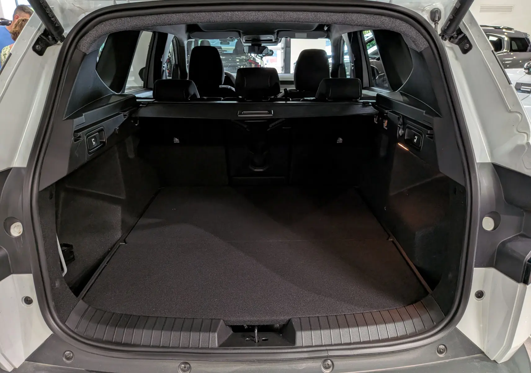 Coffre ouvert vu de l'arrière d'un Dacia Bigster blanc Glacier, avec banquette arrière et habillage intérieur noir.