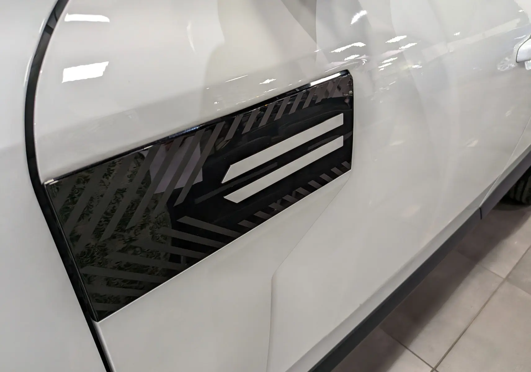 Gros plan sur la porte côté gauche du Dacia Bigster blanc glacier, mettant en valeur un insert noir décoratif à motifs géométriques.
