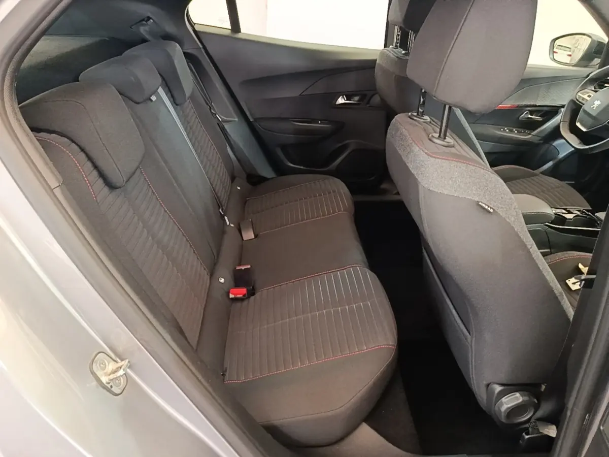 Vue intérieure côté gauche montrant la banquette arrière grise avec surpiqûres rouges du Peugeot E-2008 électrique 2023.