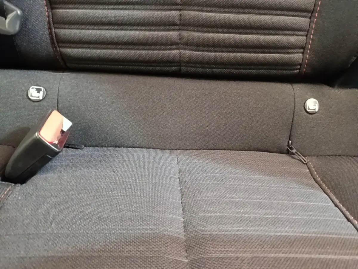 Gros plan sur la banquette arrière noire du Peugeot E-2008 électrique, montrant les fixations Isofix et la ceinture de sécurité.