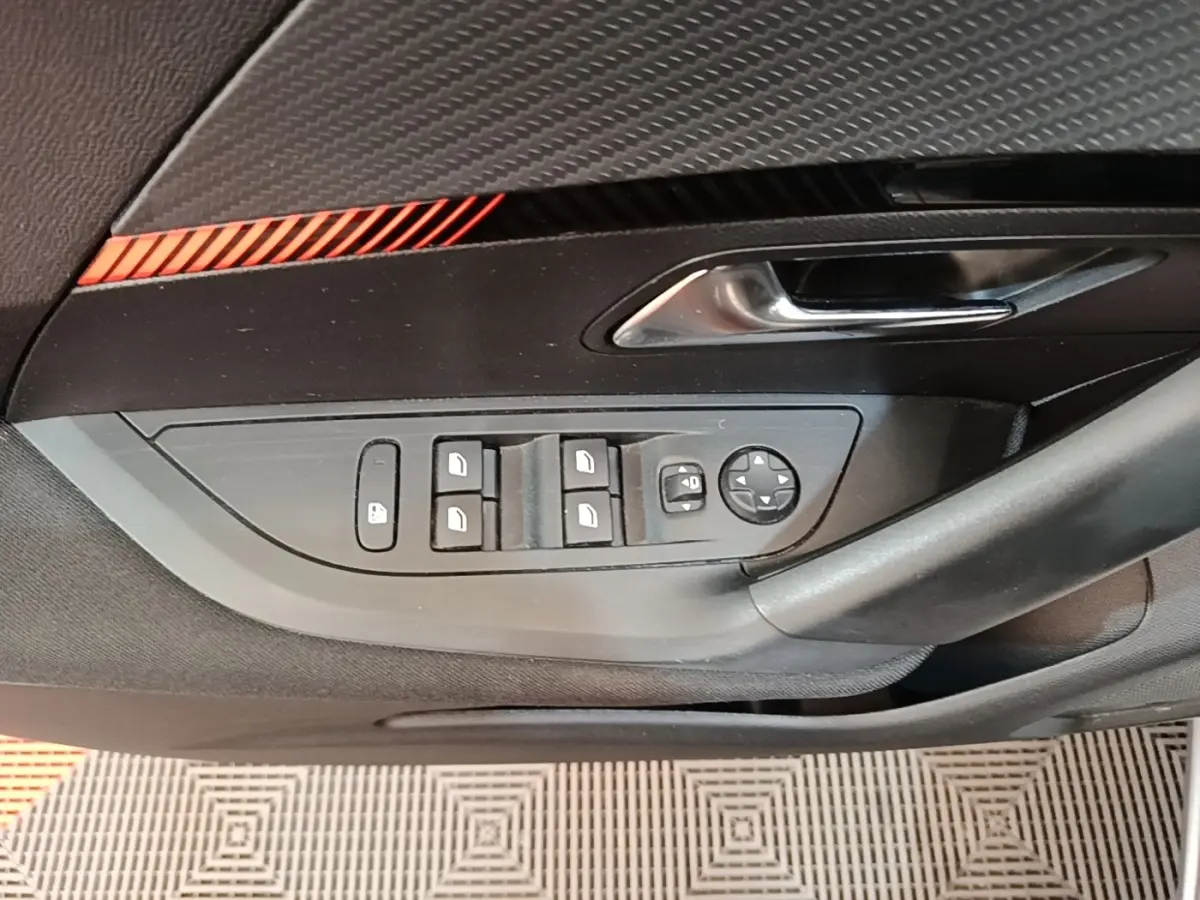 Gros plan sur la porte côté gauche du Peugeot E-2008 électrique gris clair, avec commandes des vitres et rétroviseurs.