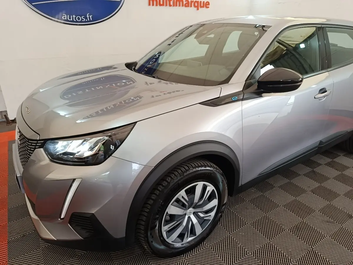 Vue 3/4 avant droit d’un Peugeot E-2008 électrique gris clair avec phares LED et jantes alliage distinctives.