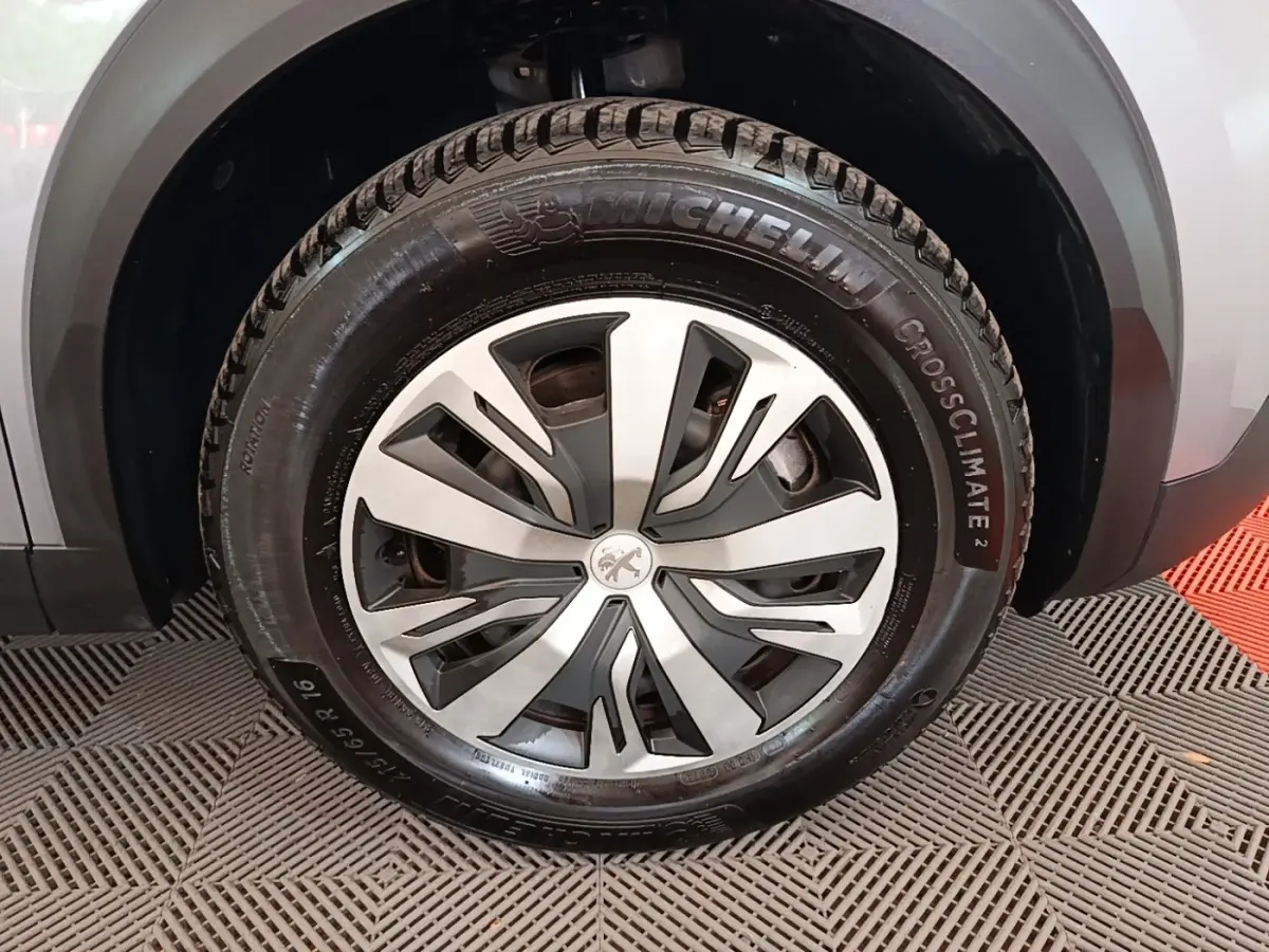 Gros plan sur la roue avant droite d’un Peugeot E-2008 électrique gris clair avec jante alliage et pneu Michelin CrossClimate 2.