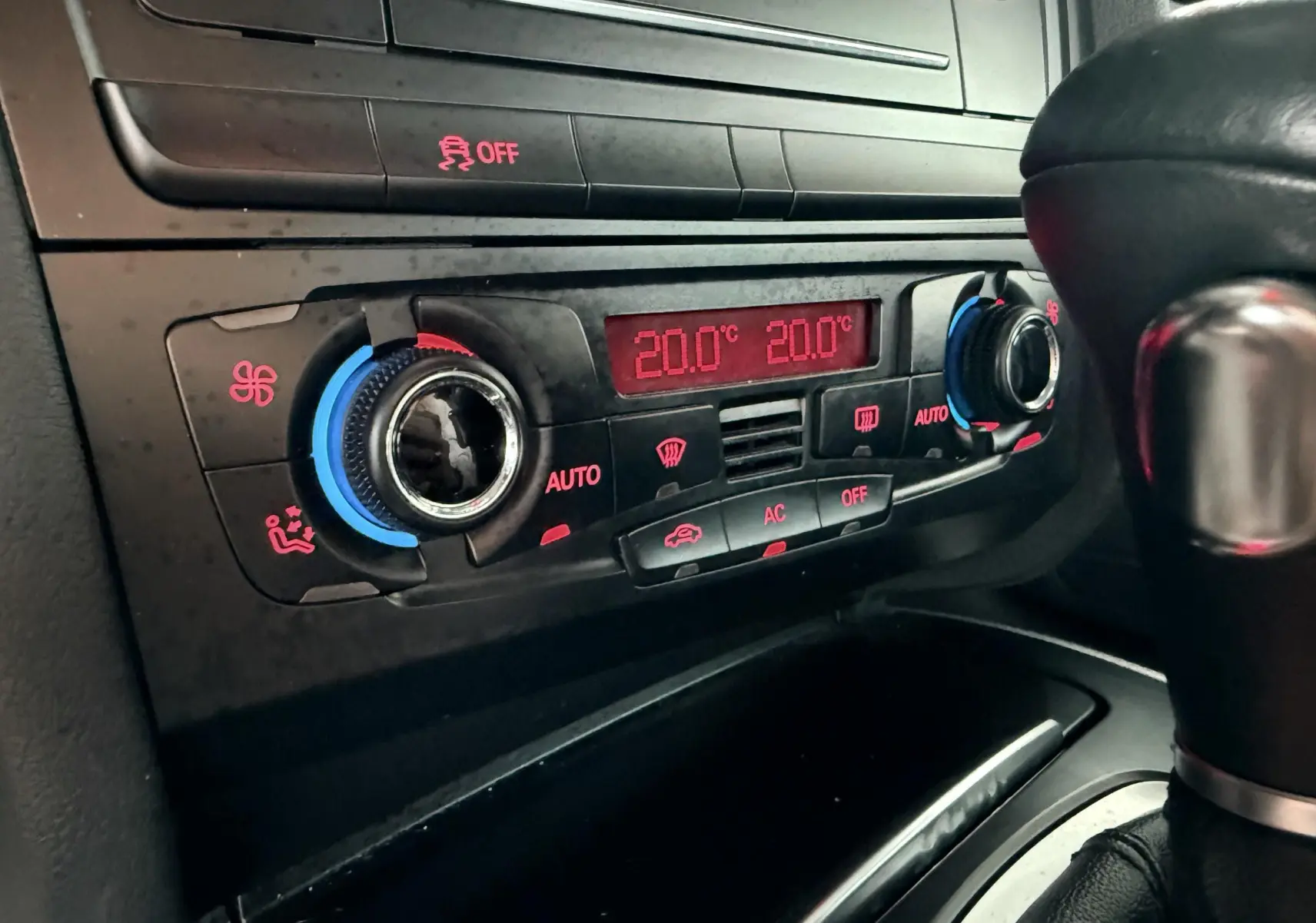 Gros plan sur la console centrale de l'Audi A5 gris, montrant la climatisation automatique réglée à 20°C.