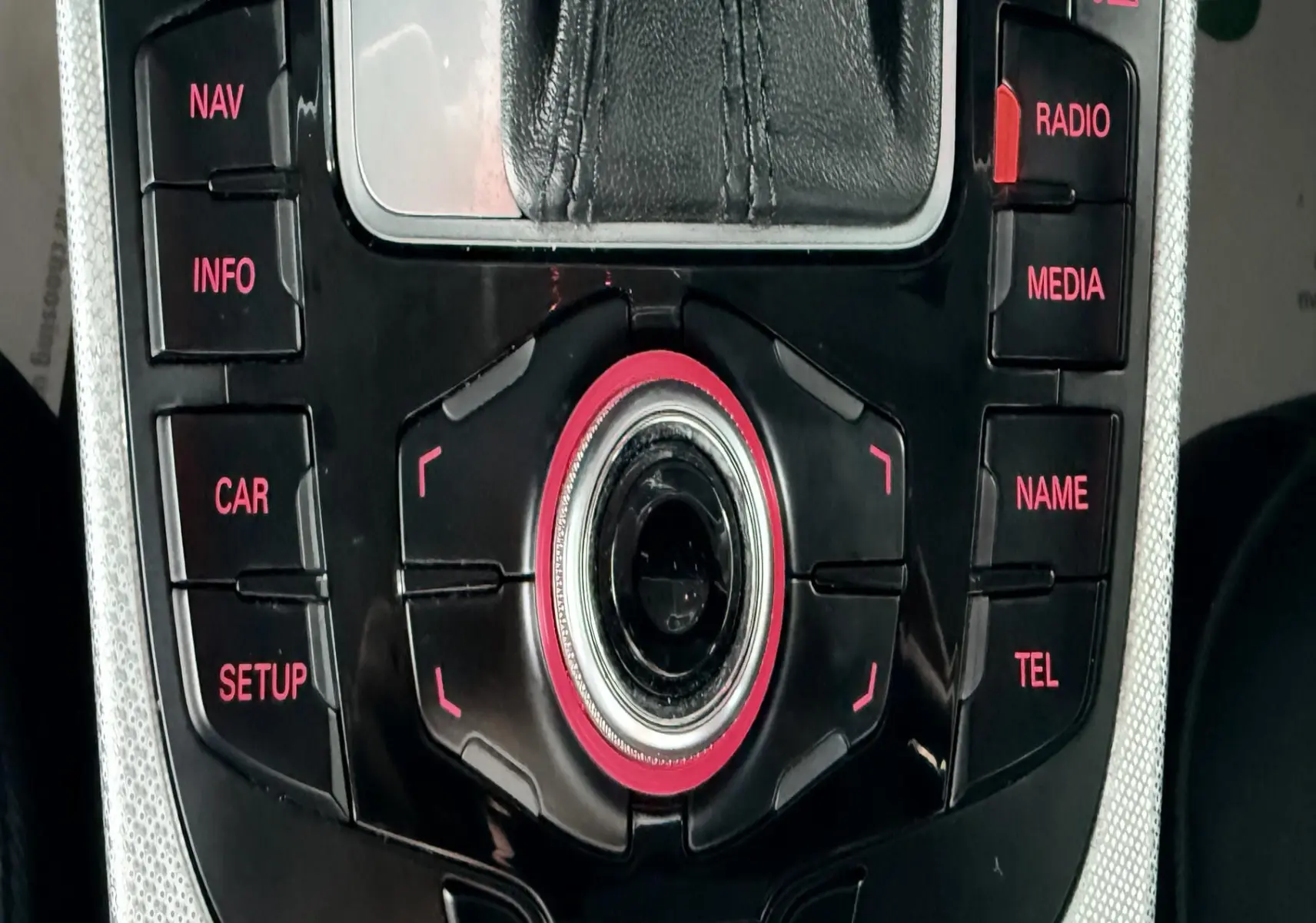 Gros plan sur la console centrale noire et argentée de l'Audi A5 2011 avec commandes multimédia rétroéclairées rouges.