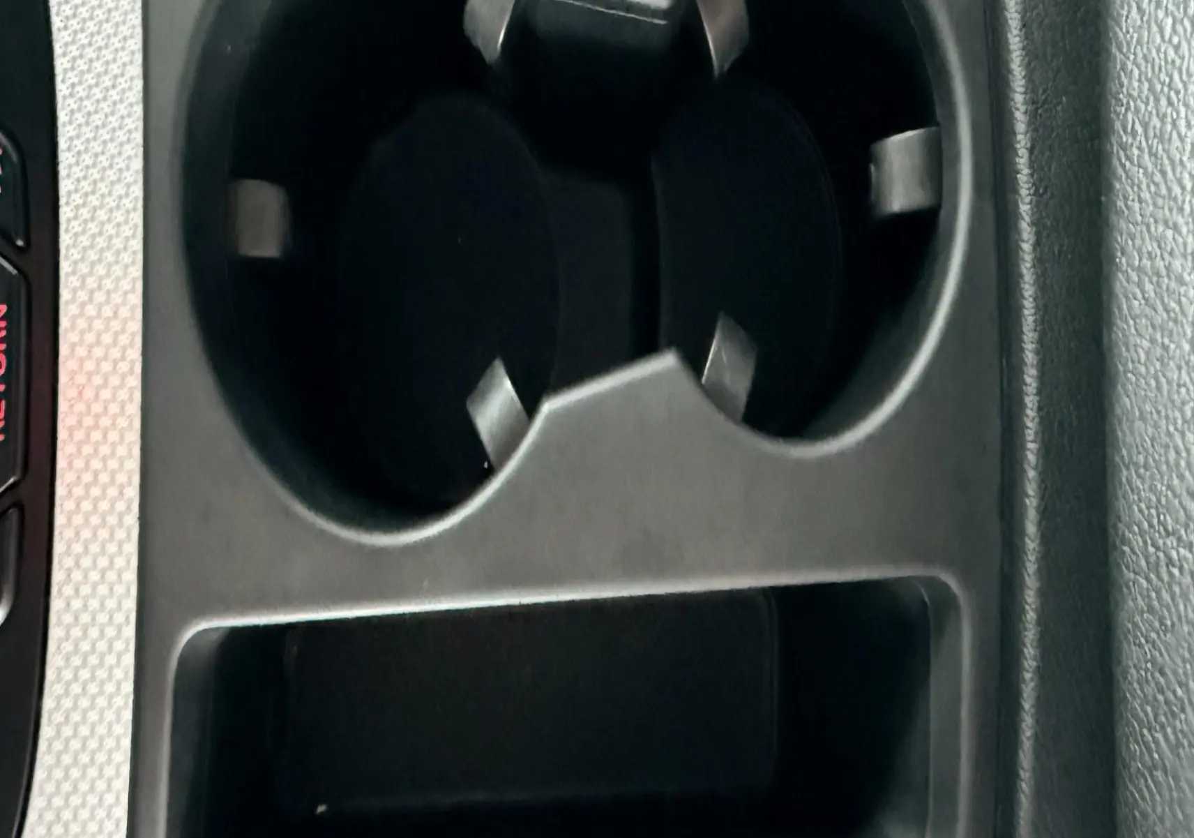 Gros plan sur les porte-gobelets noirs et le rangement central de l'Audi A5 Sportback gris, intérieur cuir noir.