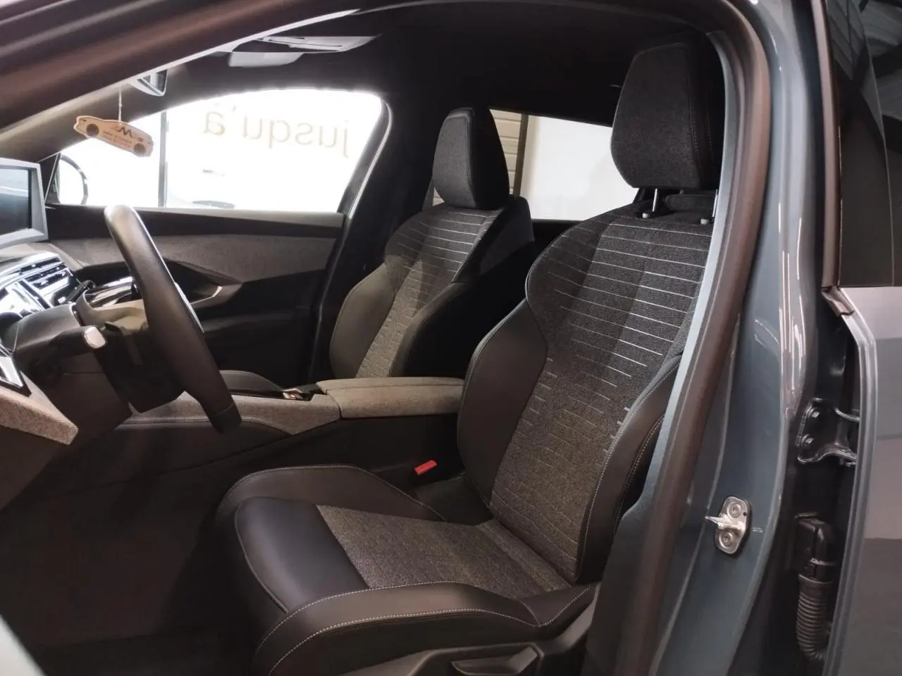 Vue intérieure côté droit du Peugeot 5008 2025 Bleu Ingaro, montrant les sièges avant en tissu et cuir avec planche de bord.