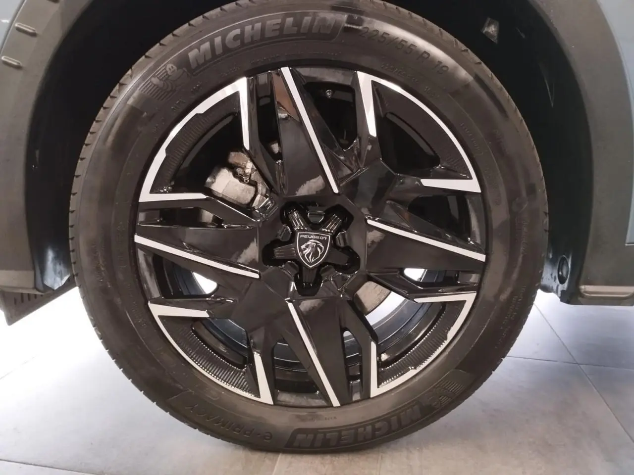 Gros plan sur la jante alliage noire diamantée 19'' avec logo Peugeot au centre, montée sur un pneu Michelin.