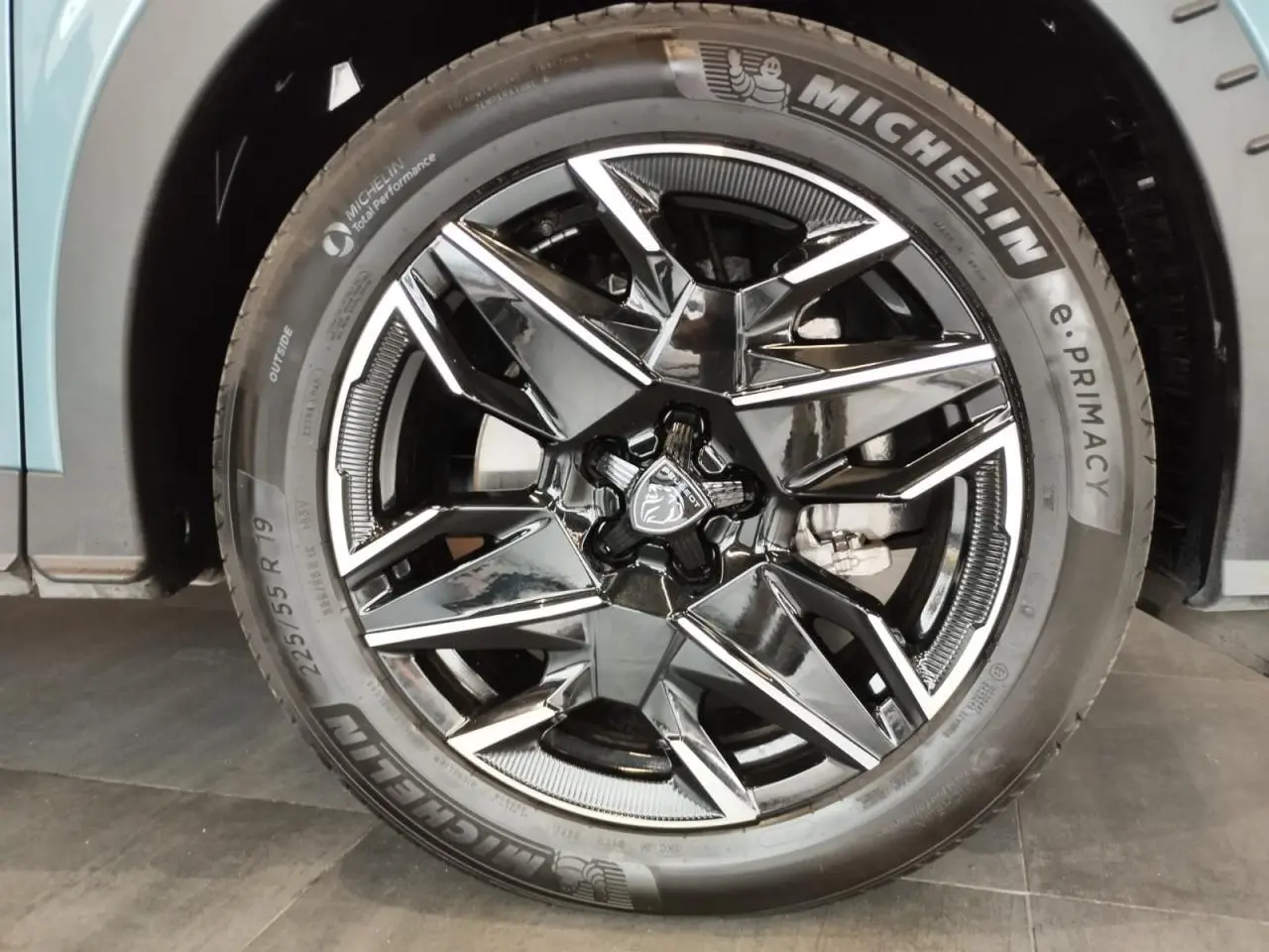 Gros plan sur la jante alliage noire diamantée 19'' du Peugeot 5008 Bleu Ingaro avec logo lion au centre.