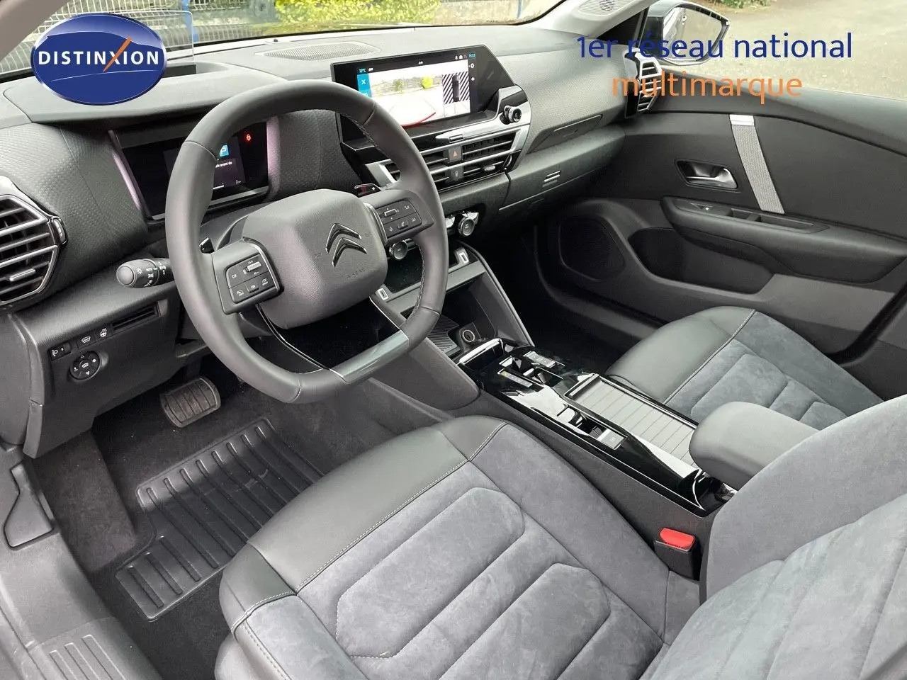 Intérieur avant de la Citroën C4 2024, vue côté conducteur, sièges gris cuir et alcantara, tableau de bord moderne avec écran tactile.