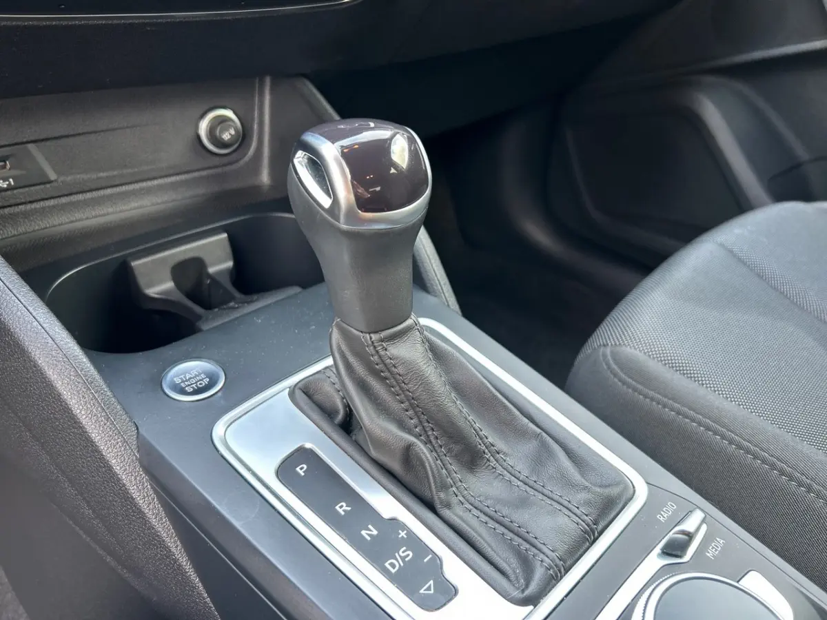 Gros plan sur la commande de boîte automatique noire et le bouton start/stop dans l'habitacle d'un Audi Q2 noir.