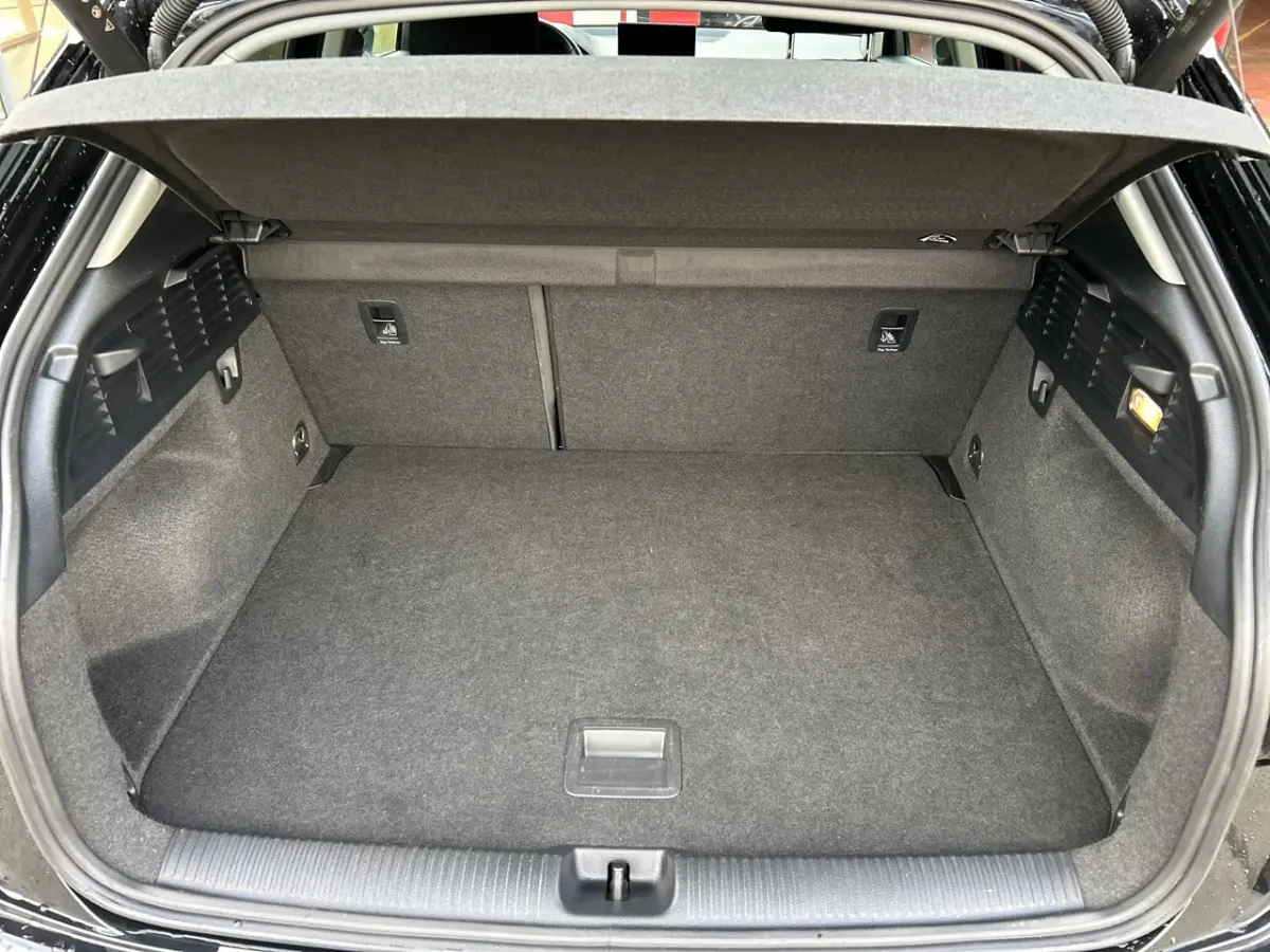 Coffre ouvert vu de l'arrière d'un Audi Q2 noir 2023, montrant un espace de chargement propre et bien fini.