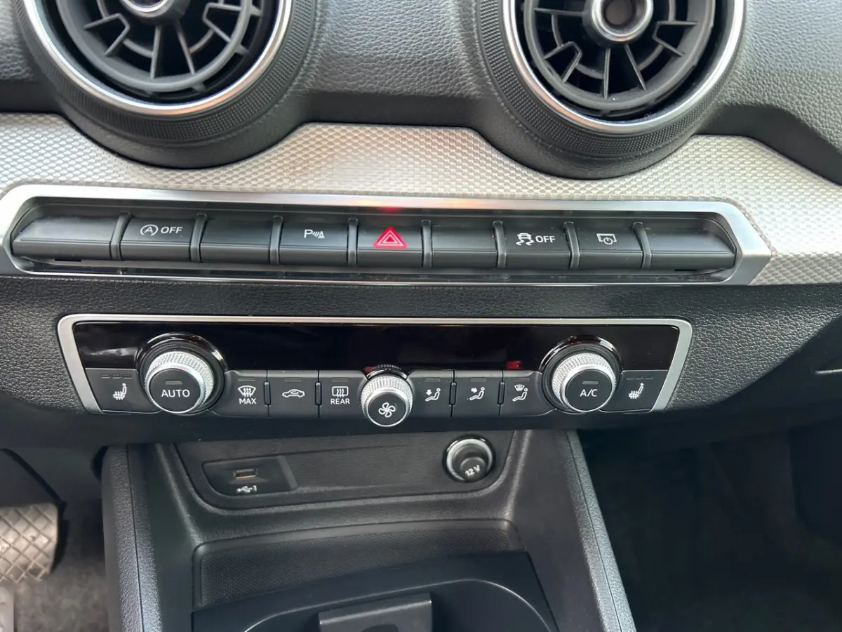 Détail du tableau de bord noir de l'Audi Q2 35 TFSI 2023 avec commandes climatisation et ventilation.