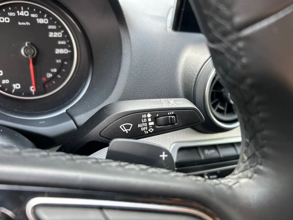 Gros plan sur la commande des essuie-glaces et le volant cuir noir de l'Audi Q2 35 TFSI 2023 côté gauche.