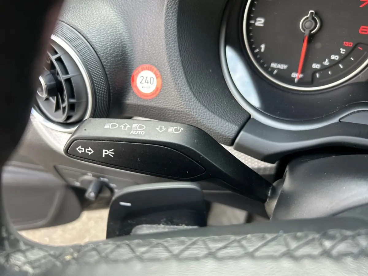 Gros plan sur le commodo gauche et le combiné d'instruments du tableau de bord noir de l'Audi Q2 35 TFSI 2023.