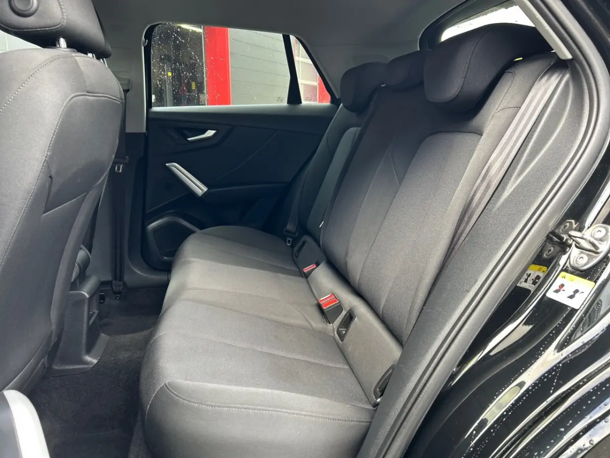 Vue côté droit sur la banquette arrière noire de l'Audi Q2 35 TFSI 150 S Line 2023 avec portes ouvertes.