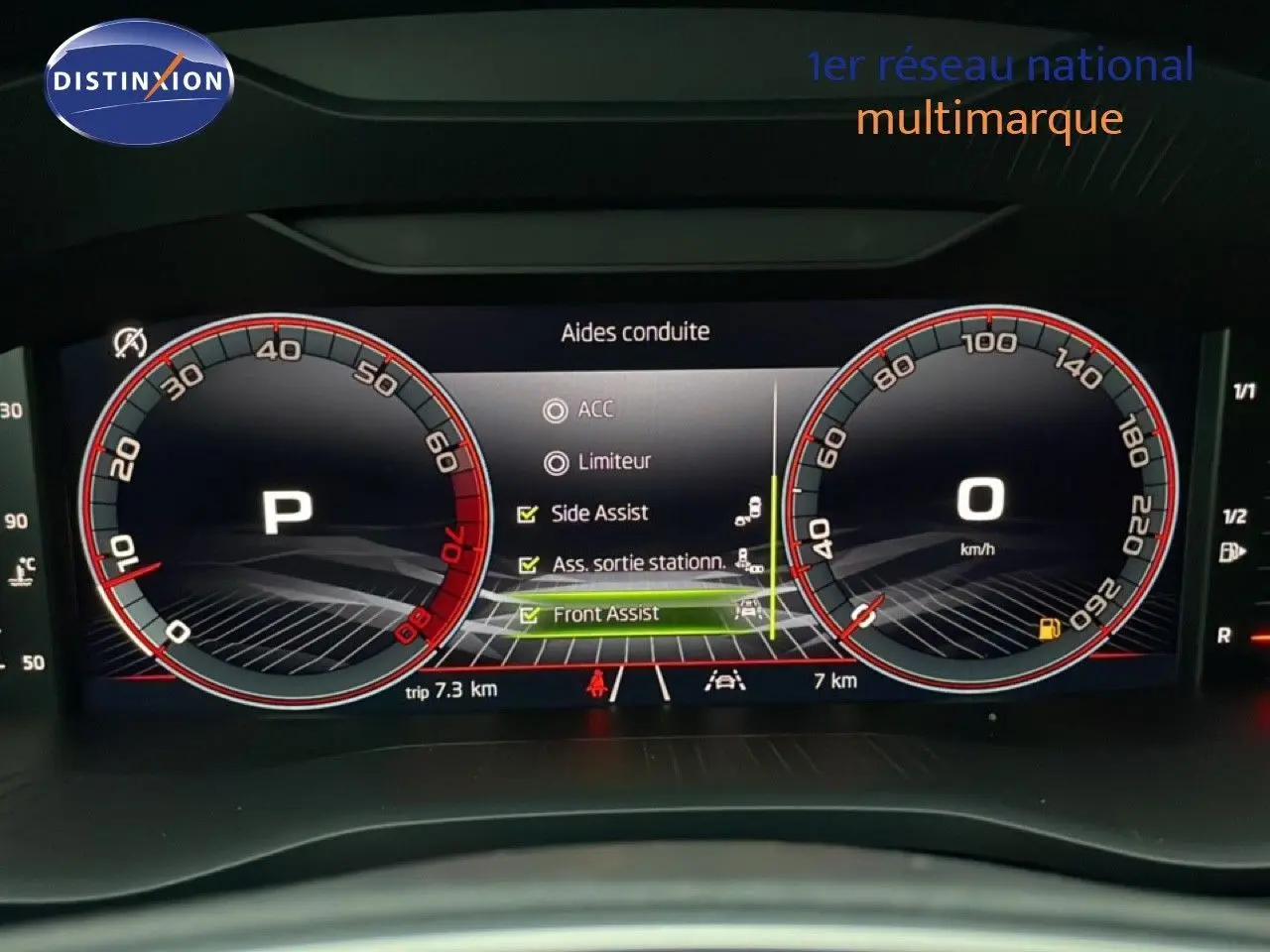 Vue rapprochée du tableau de bord numérique du Skoda Karoq gris argent, affichant les aides à la conduite activées.