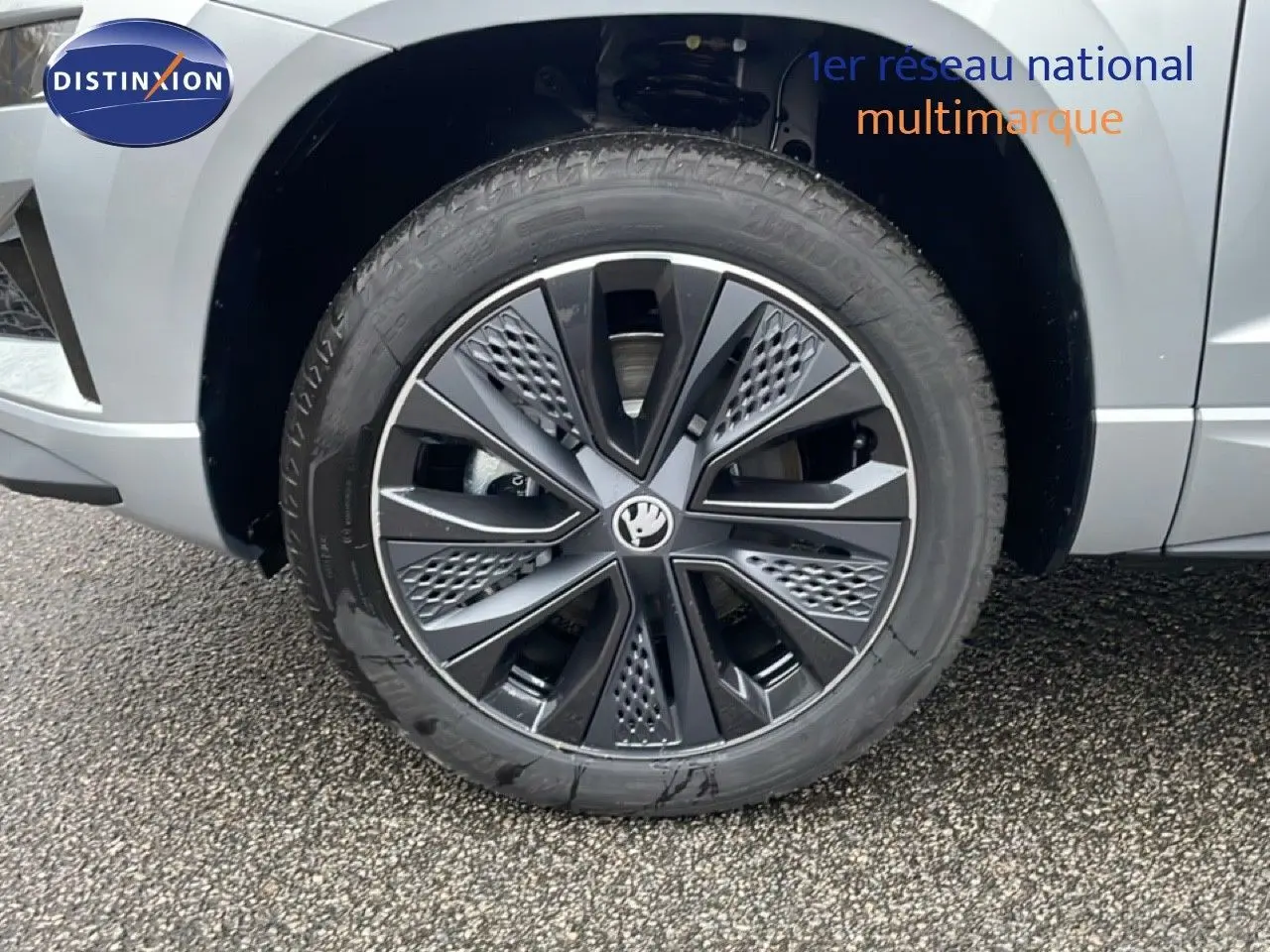 Gros plan sur la roue avant gauche avec jante noire et grise du SKODA KAROQ gris argent métallisé 2025.