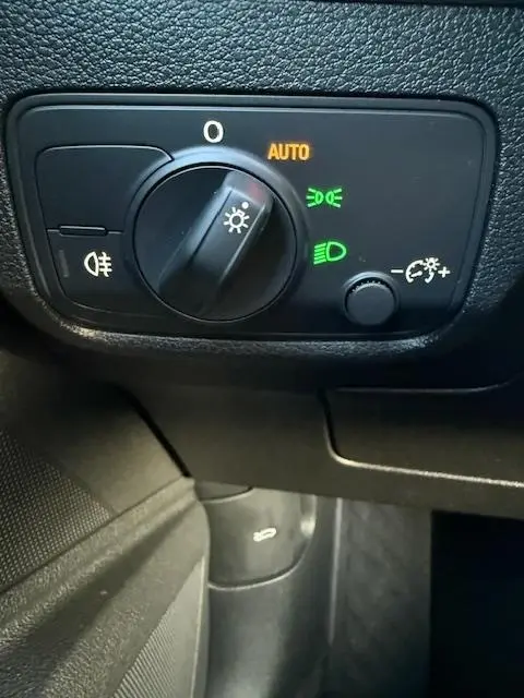 Gros plan sur le bouton de commande des phares avec réglage automatique, intérieur noir de l'Audi Q2 35 TFSI 2023.