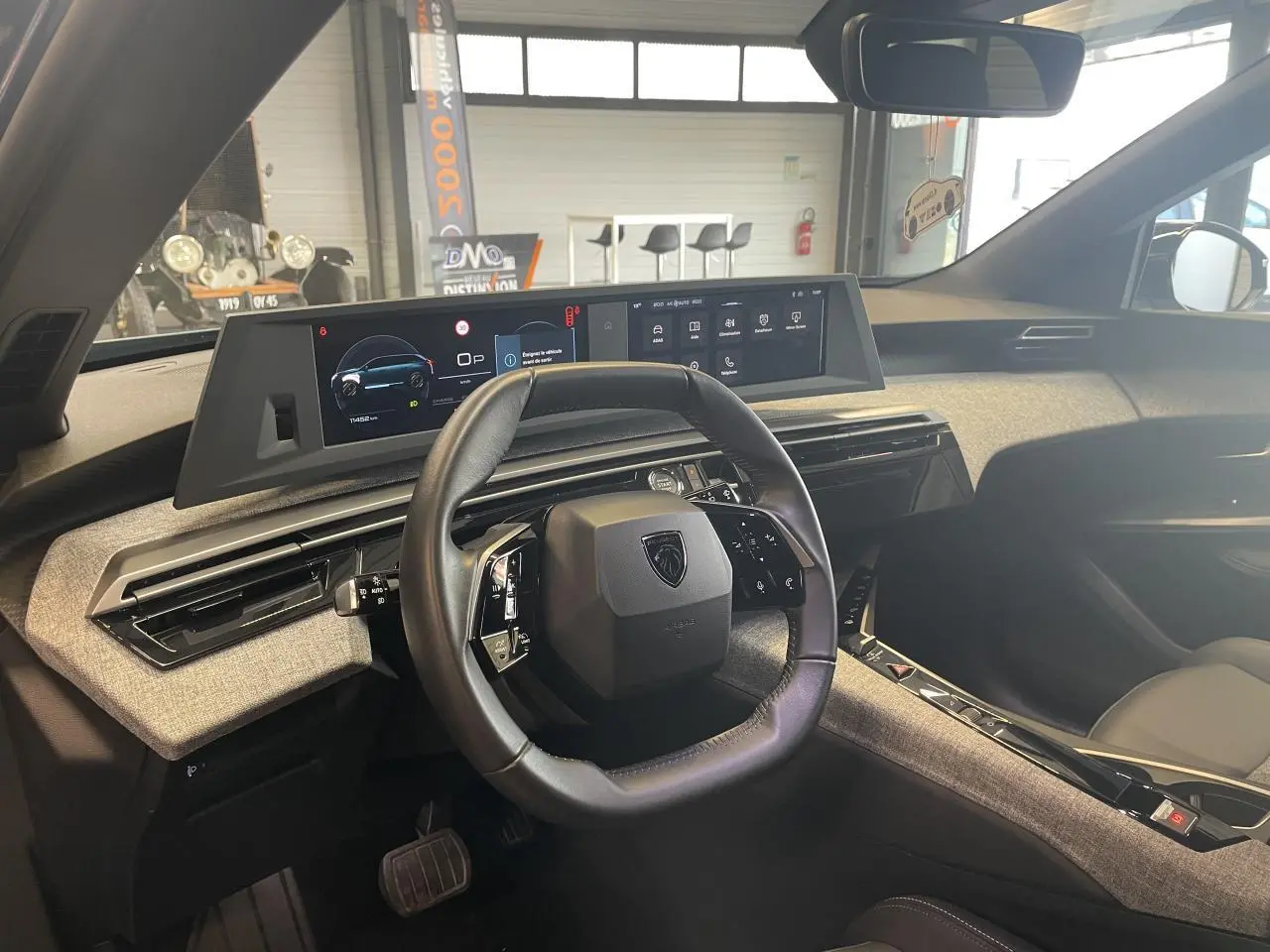 Vue intérieure du tableau de bord du Peugeot 5008 2025, volant compact cuir noir et double écran HD panoramique.